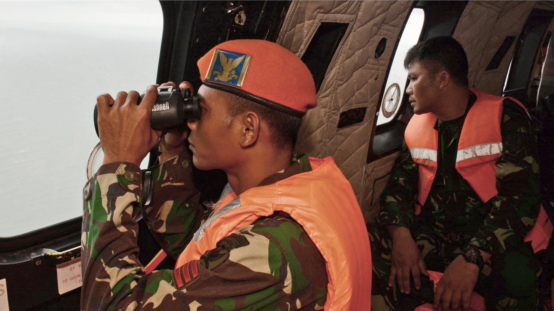 Jan. 1, 2015: A crew member of an Indonesian Air Force Super Puma helicopter of 6th Air Squadron uses a pair of binoculars to scan the horizon during a search operation for the victims of AirAsia Flight 8501 over Java Sea, Indonesia