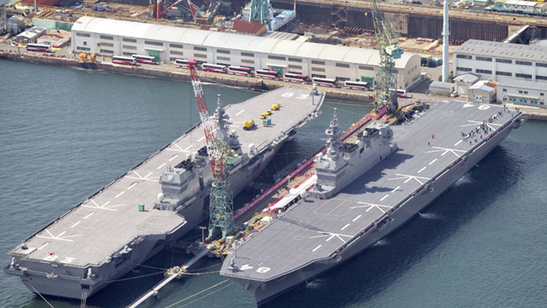 Japan Maritime Self-Defence Force's helicopter carrier Kaga, right, along with Izumo, left, is seen in Yokohama, south of Tokyo, Wednesday, March 22, 2017. Japan's navy commissioned a new helicopter carrier, "Kaga," on Wednesday, which has become the second Izumo-class destroyer to join its fleet. Kaga is 248 meters (814 feet) long, 38 meters (125 feet) wide, and can carry up to fourteen helicopters. (Yoshitaka Sugawara/Kyodo News via AP)