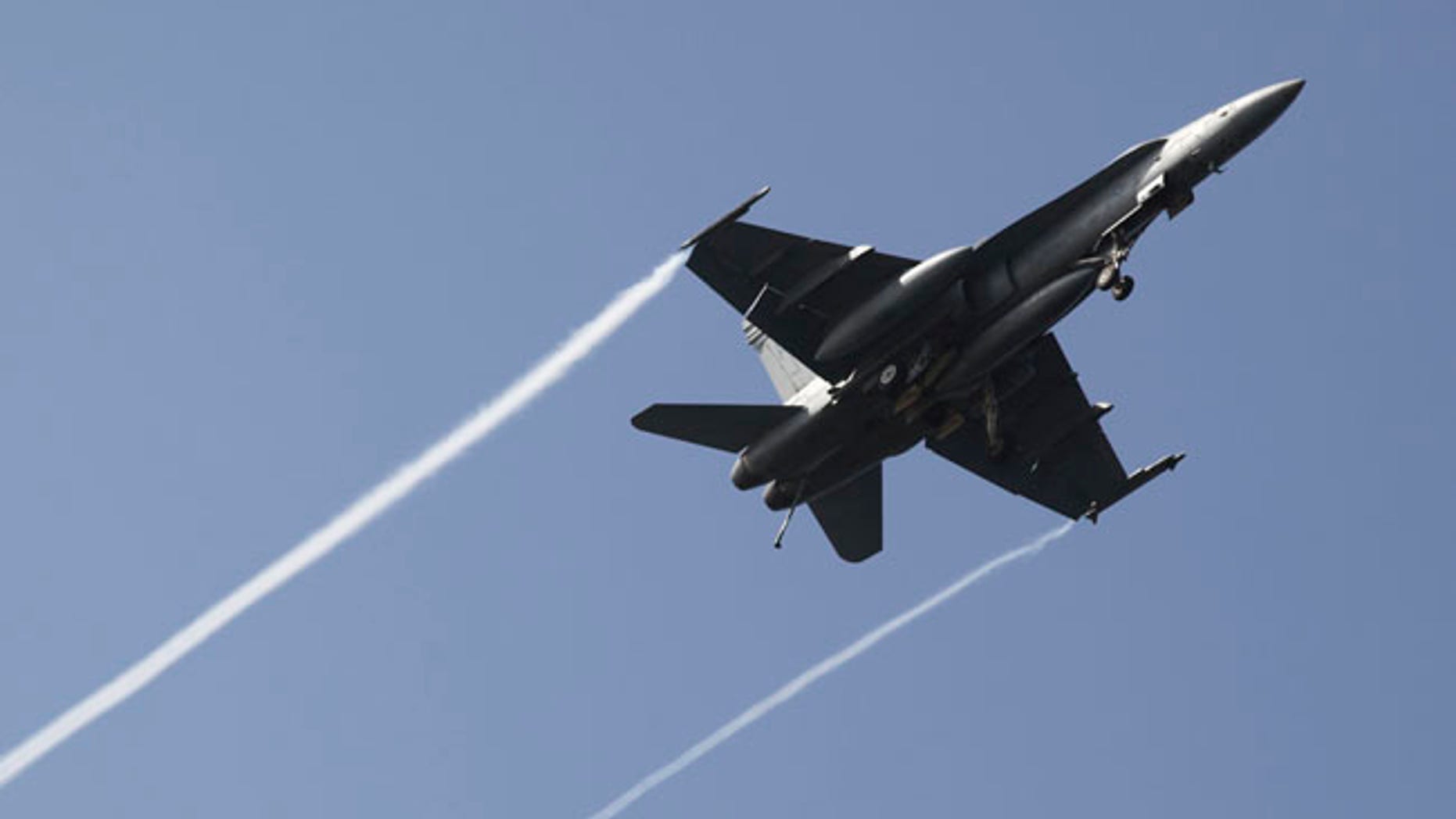 In this Monday, March 20, 2017 photograph, an F-18 fighter jet flies over the USS George H.W. Bush as the vessel travels toward the Strait of Hormuz. The arrival of the nuclear-powered aircraft carrier to the Persian Gulf marks the first such deployment under new U.S. President Donald Trump. (AP Photo/Jon Gambrell)