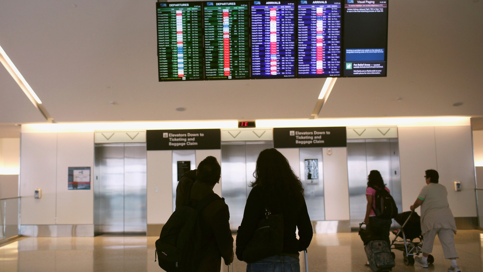 Airline passengers look at a flight status board at San Francisco International Airport in San Francisco