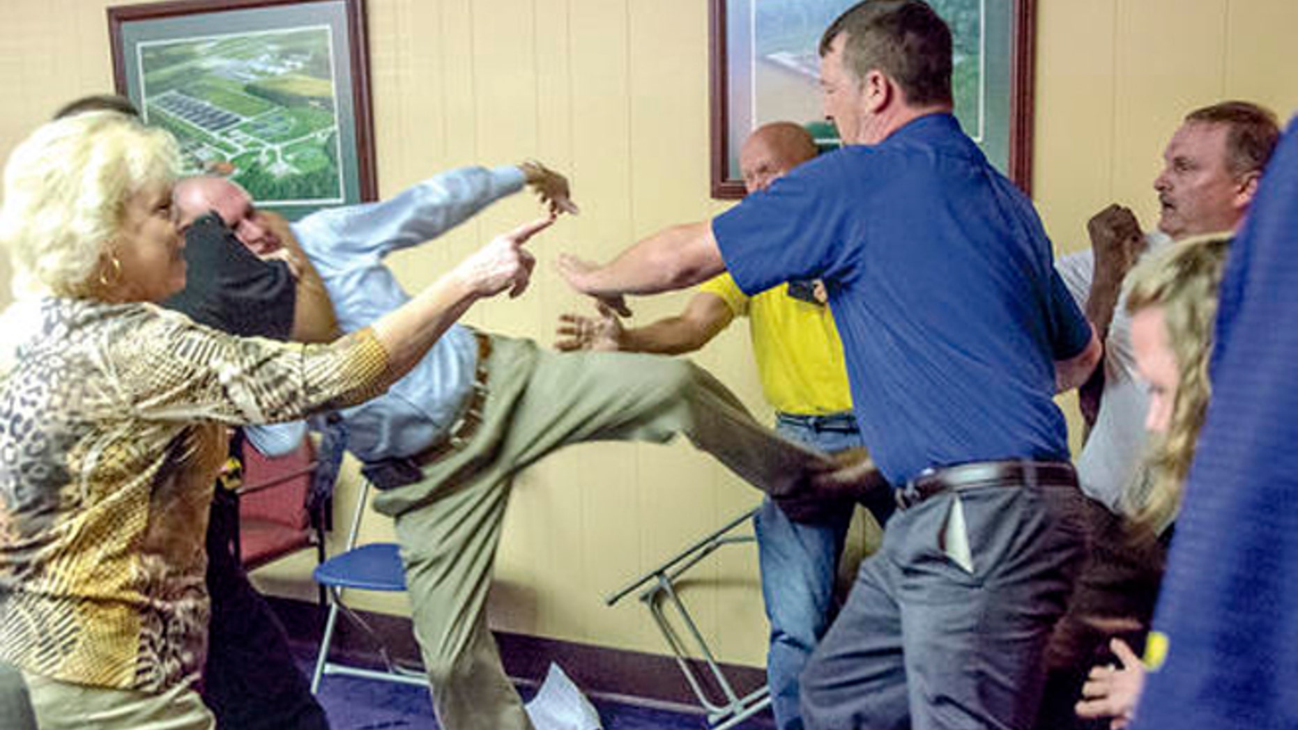 Alexander City, Ala Mayor Charles Shaw, left, is restrained by an officer after a fight broke out between him and councilman Tony Goss, far right, during a meeting of the Alexander City City Council in Alexander City, Ala. on Monday, April 25, 2016.