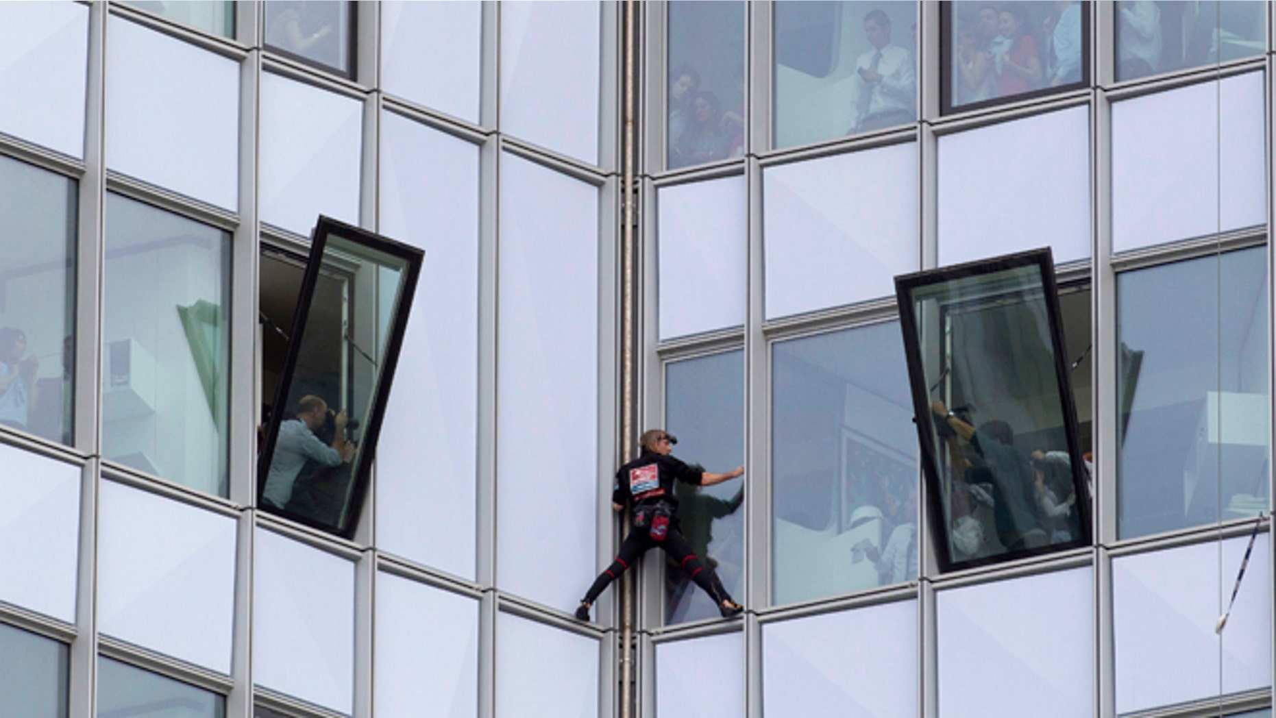 May 10, 2012: People look out of their windows as French urban climber Alain Robert, known as 'Spiderman', climbs up the 758 feet high First Tower, the tallest skyscraper in France, outside Paris.