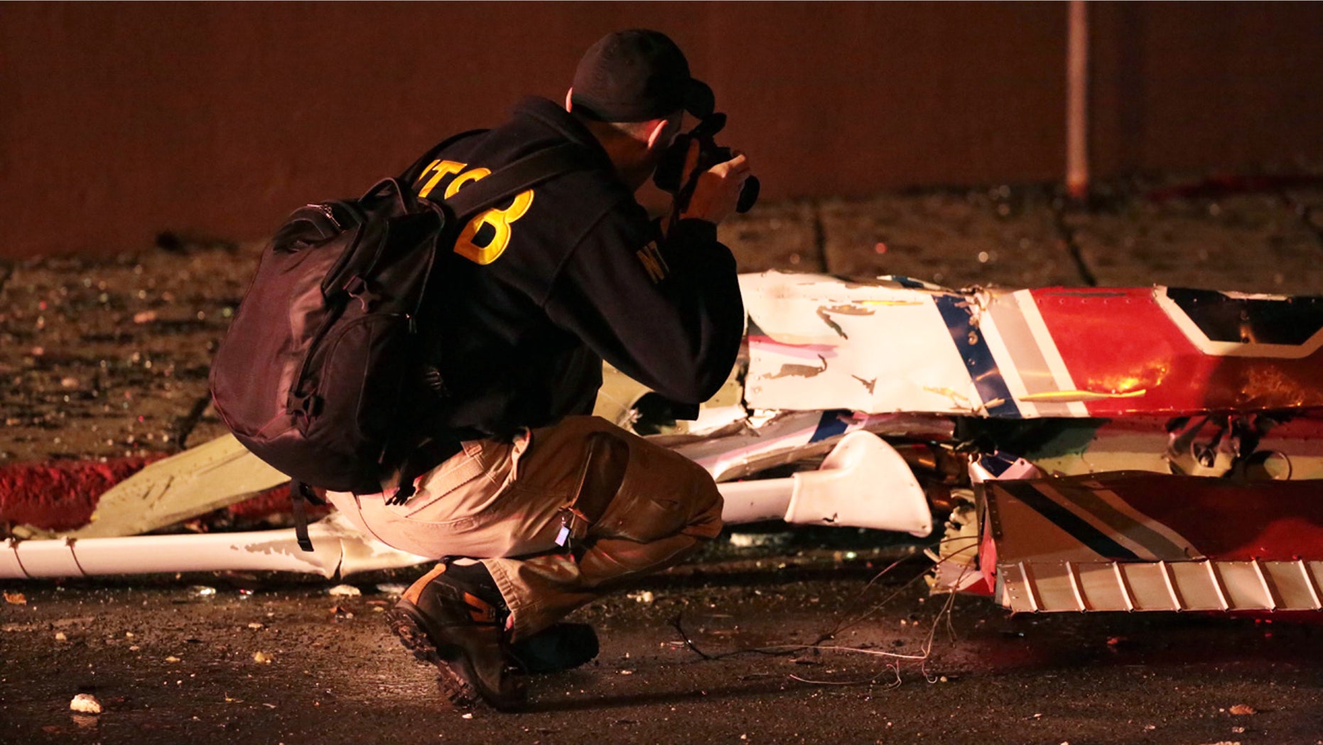 Dec. 29, 2015: A National Transportation Safety Board investigator takes photos at the scene of an aircraft crash in Anchorage, Ak. A small plane clipped a downtown Anchorage office building and then slammed into a nearby commercial building early Tuesday, igniting a fire and killing the pilot, authorities said. (Loren Holmes/Alaska Dispatch News via AP)