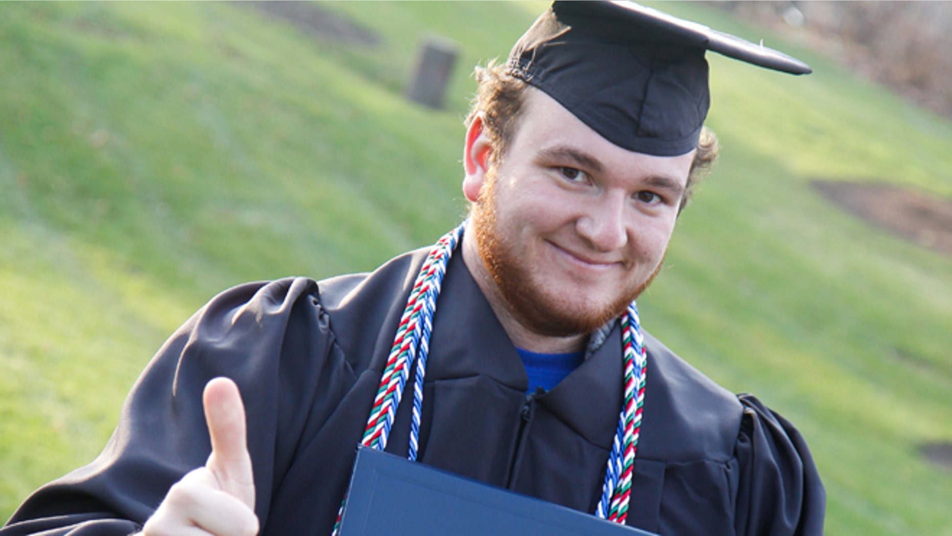 This 2013 photo shows Alex Benda, 22, anticipating his graduation from the University of Michigan-Flint. He's selling ad space on his graduation cap in an effort to pay off his college debt by May.