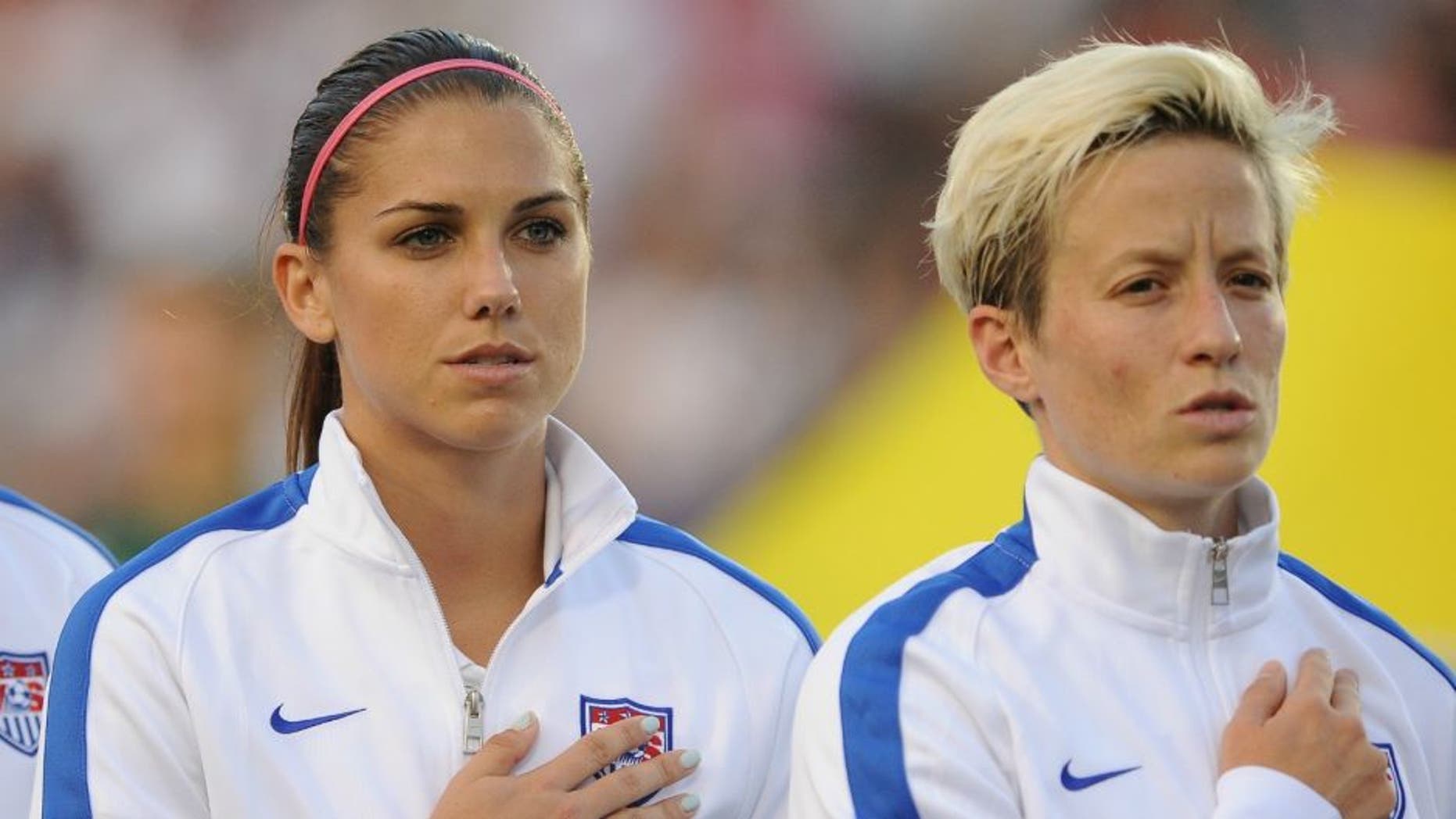 CARY, NC - AUGUST 20: Lauren Holiday #12, Alex Morgan #13 and Megan Rapinoe #15 of the U.S. women's national team stand at attention during the National Anthem prior to their match against the Swiss women's national team at WakeMed Soccer Park on August 20, 2014 in Cary, North Carolina. (Photo by Lance King/Getty Images)