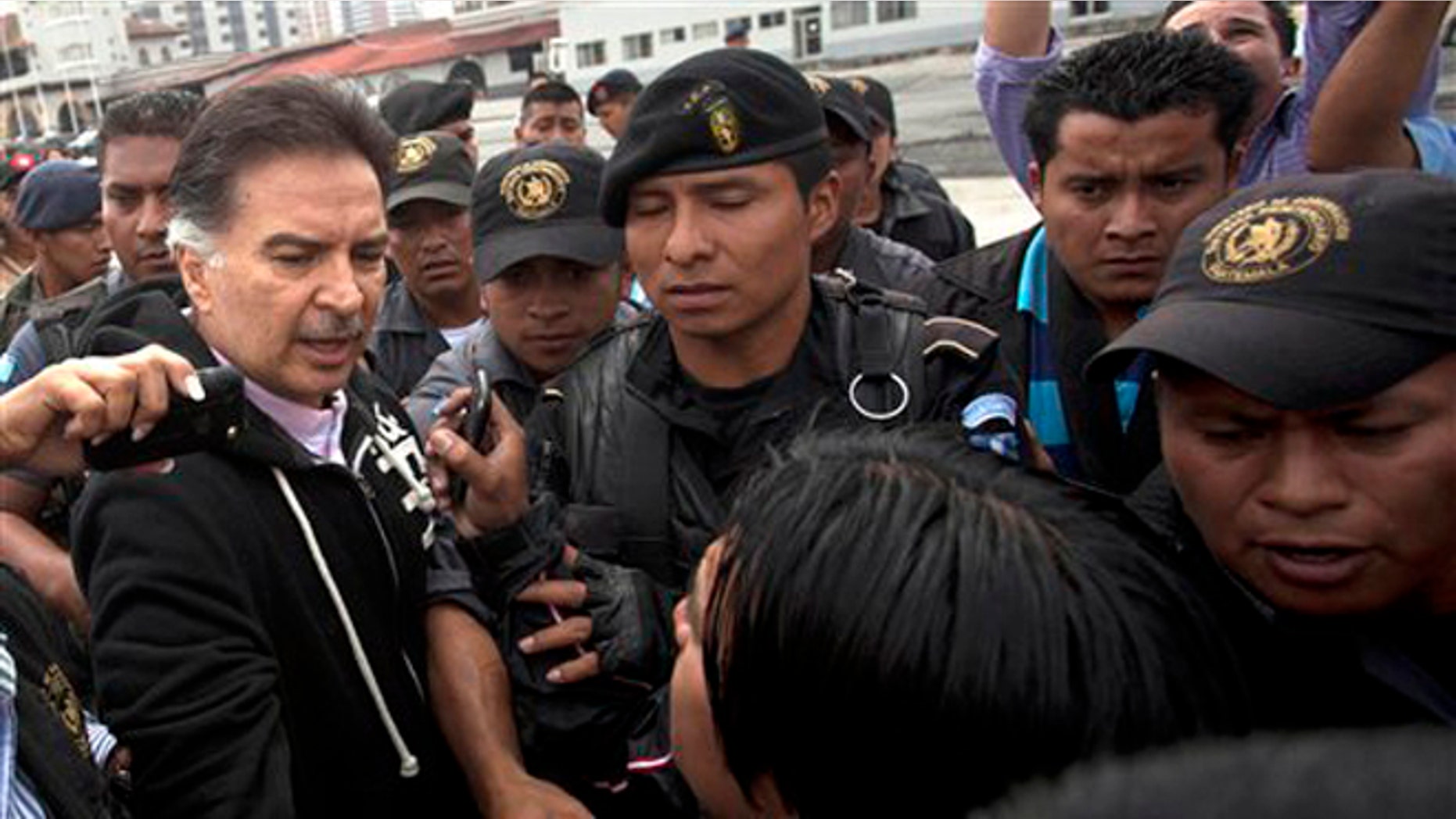 Former president of Guatemala, Alfonso Portillo, left, speaks to the press as he is led by police to an aircraft that will fly him to the United States Friday, May 24, 2013.
