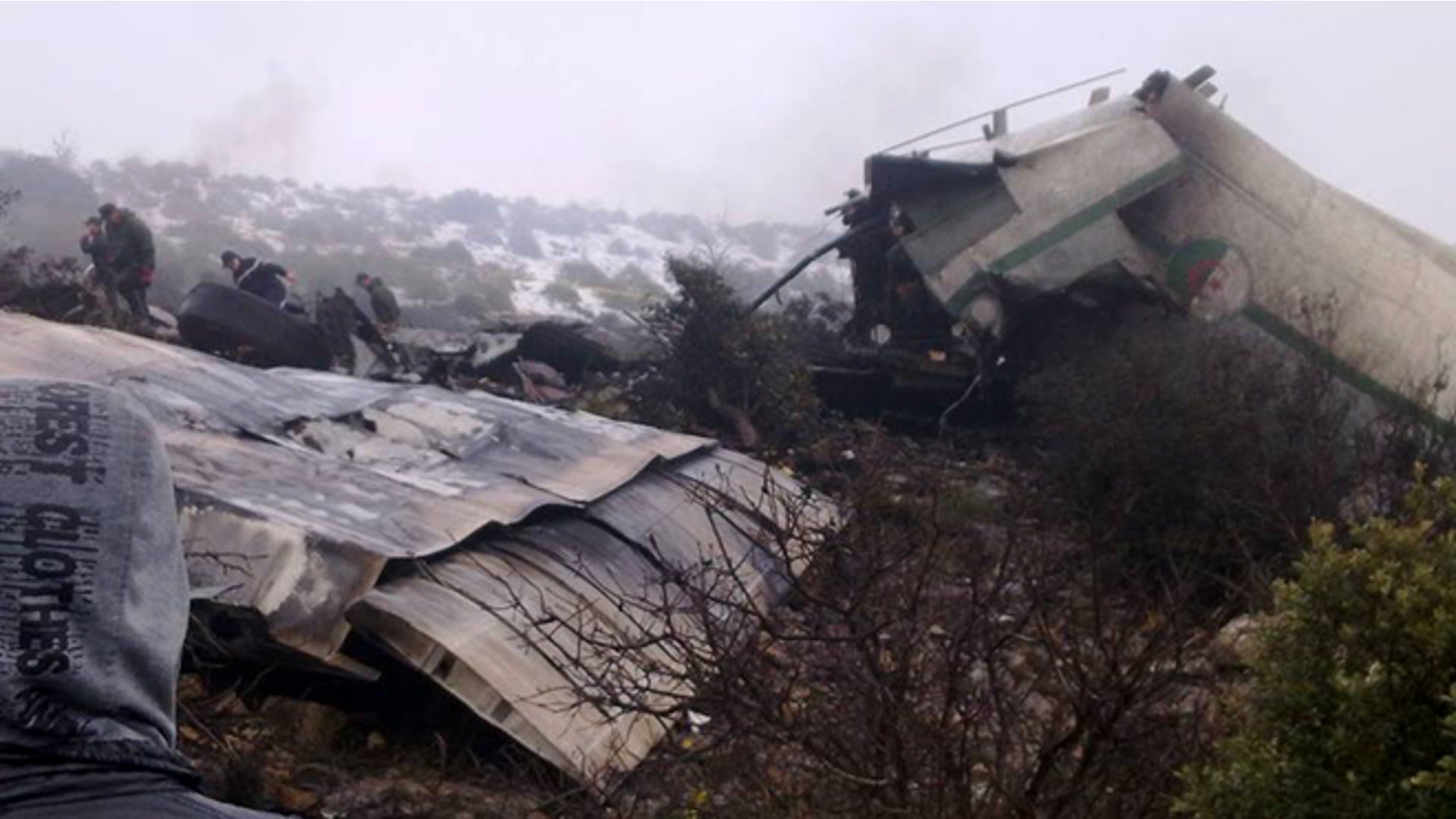 Feb. 11, 2014: A man watches rescue workers working at the wreckage of Algerian military transport aircraft after it slammed into a mountain in the country's rugged eastern region.