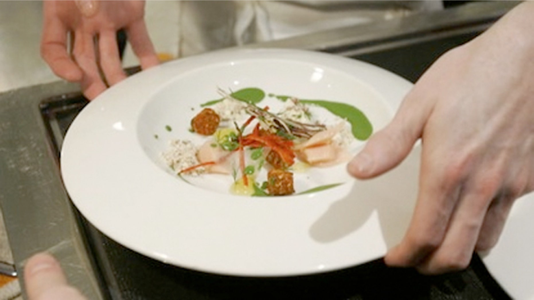 Chef Grant Achatz places a dish on a server's tray at Alinea in Chicago.