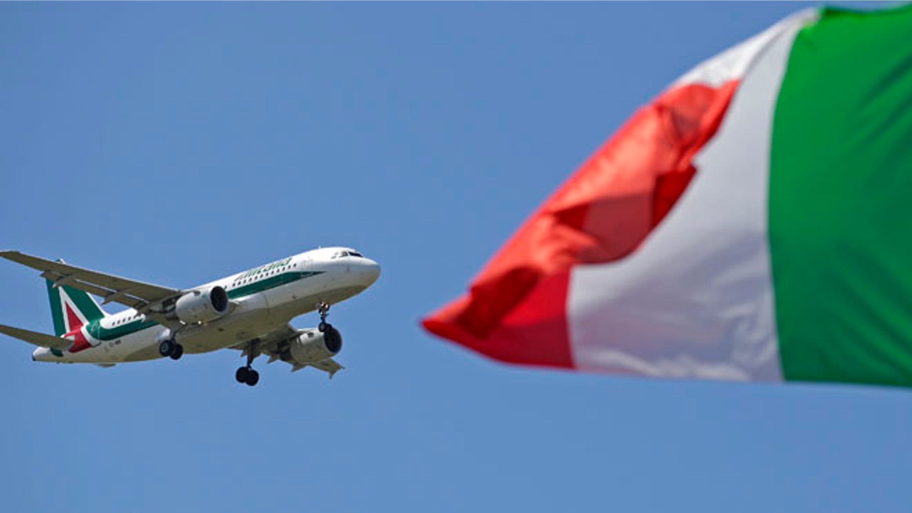 July 31, 2014: An Italy flag flutters as an Alitalia airplane approaches to land at Fiumicino airport in Rome.