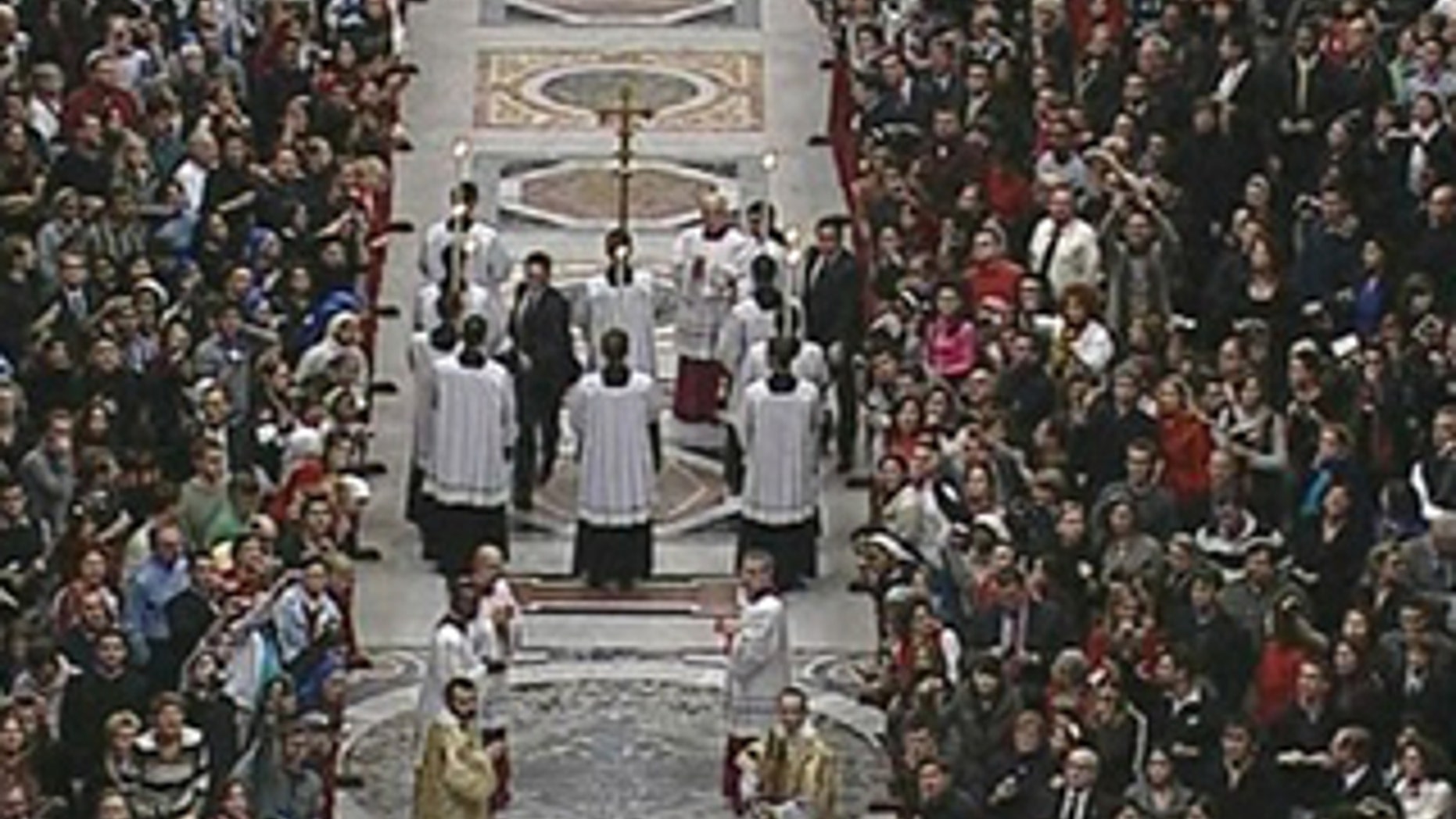 In this image made from Vatican television via APTN, Vatican security, at center of aisle in black, make their way towards Pope Benedict XVI, not seen, after he was knocked down during Christmas Mass in St. Peter's Basilica at the Vatican, Thursday, Dec. 24, 2009. A woman jumped the barriers in St. Peter's Basilica and knocked down the pontiff as he walked down the main aisle to begin Christmas Eve Mass on Thursday, a Vatican spokesman said. The Rev. Ciro Benedettini said the 82-year-old pope quickly got up and was unhurt. (AP Photo/CTV via APTN) ** AP CLIENTS ONLY **