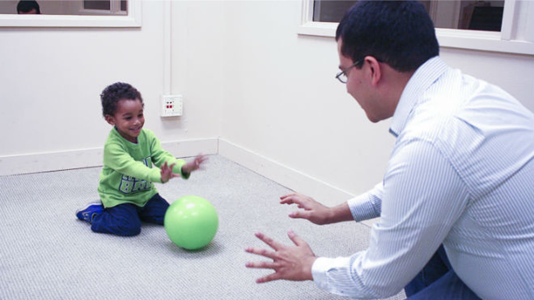 A researcher rolls a ball with a toddler, engaging in the type of reciprocal play that primes the child to exhibit future altruistic behaviors. (Stanford/Chia-wa Ye)