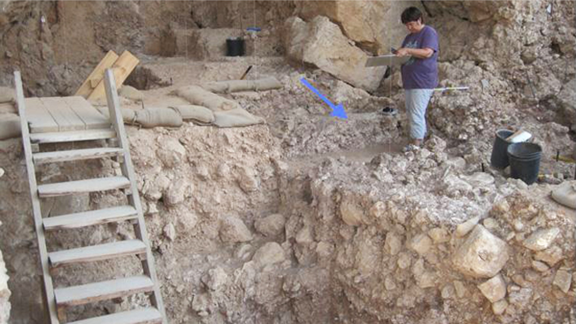 Qesem Cave near the central Israel town of Rosh Ha'ayin, with an arrow pointing to a 300,000-year-old hearth recently uncovered.