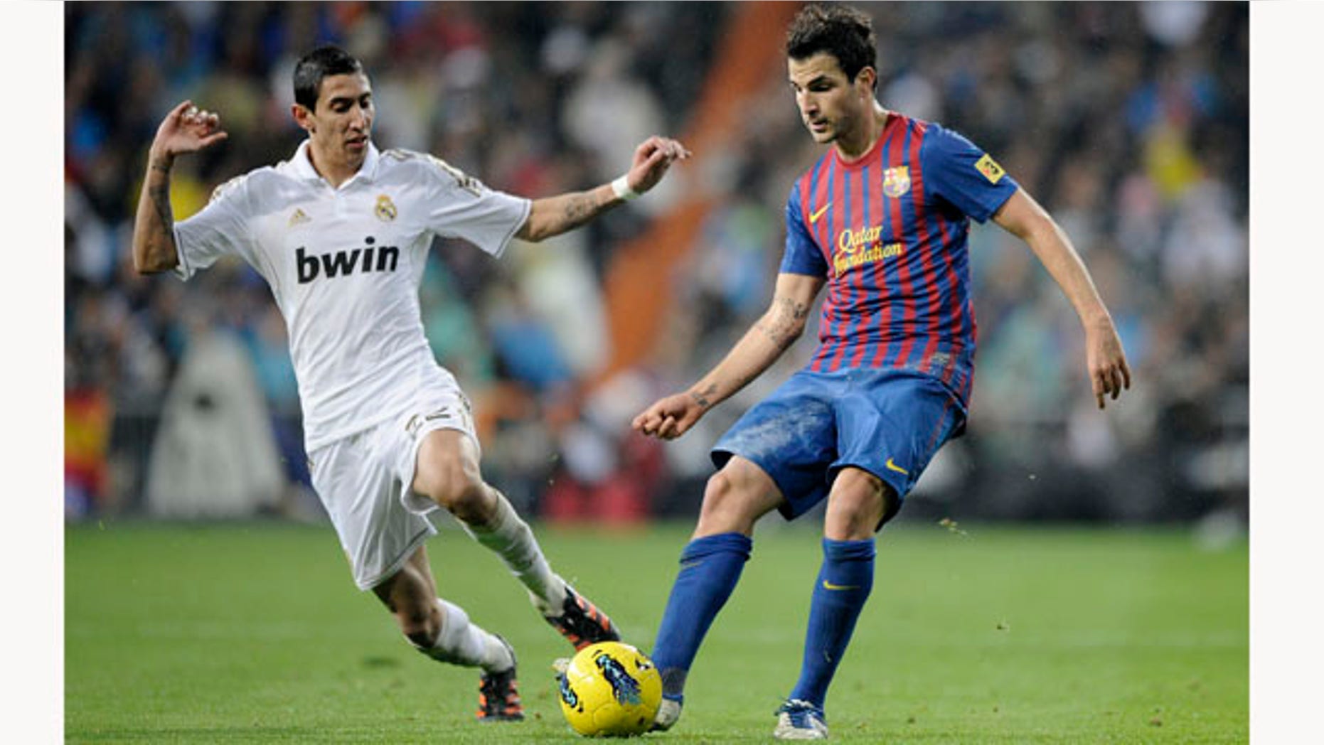Real Madrid's Angel Di Maria from Argentina, left, duels for the ball with Barcelona's Cesc Fabregas, right, during their Spanish La Liga soccer match at the Santiago Bernabeu stadium, in Madrid, Saturday, Dec. 10, 2011. (AP Photo/Daniel Ochoa de Olza)