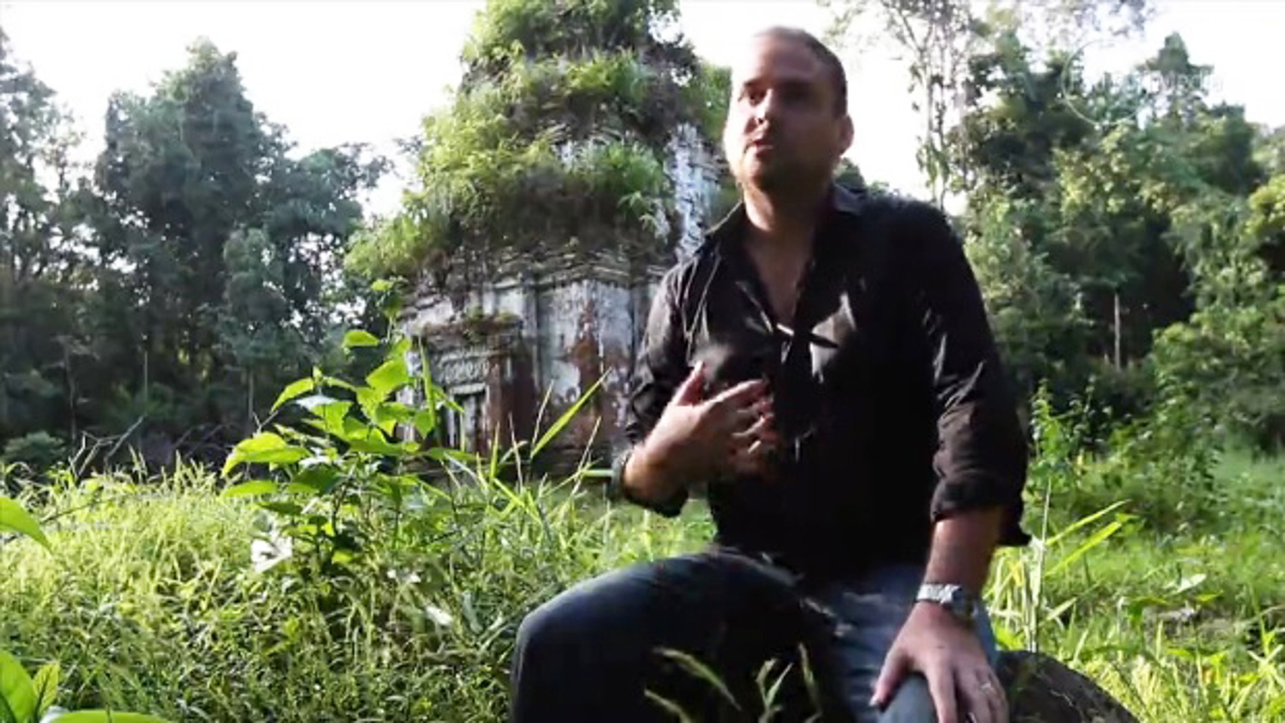 A screenshot from a video interview shows an archaeologist in the Siem Reap region before a relic of an entire Agkor city discovered using new maps acquired with LIDAR technology.