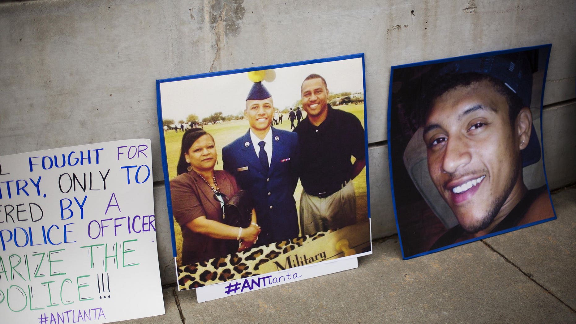 A photo of Anthony Hill, center, with family members stands during a demonstration against his shooting death in March.