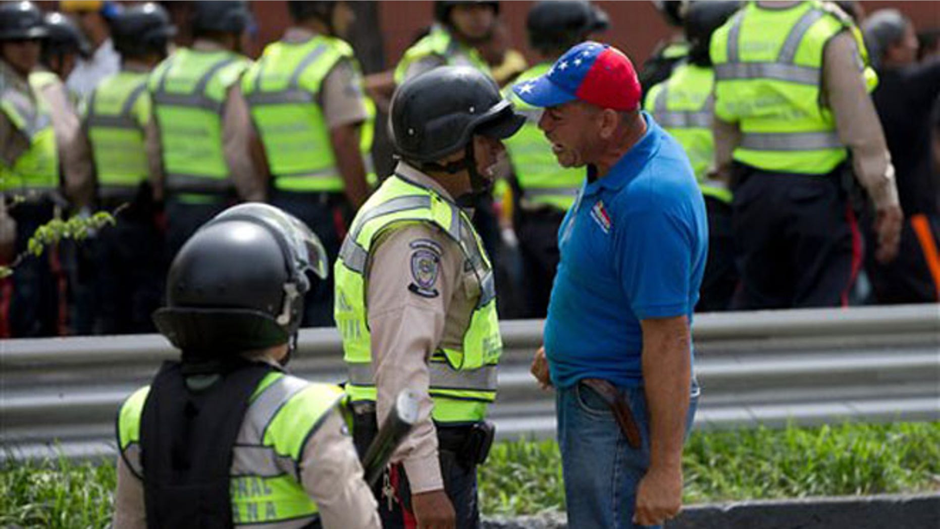 An anti-government demonstrator argues with a Bolivarian National Police officer during a march toward the headquarters of the national electoral body, CNE, in Caracas, Venezuela, Wednesday, May 18, 2016. The opposition was blocked from marching to the CNE as they demand the government allow it to pursue a recall referendum against Venezuela's President Nicolas Maduro. (AP Photo/Fernando Llano)