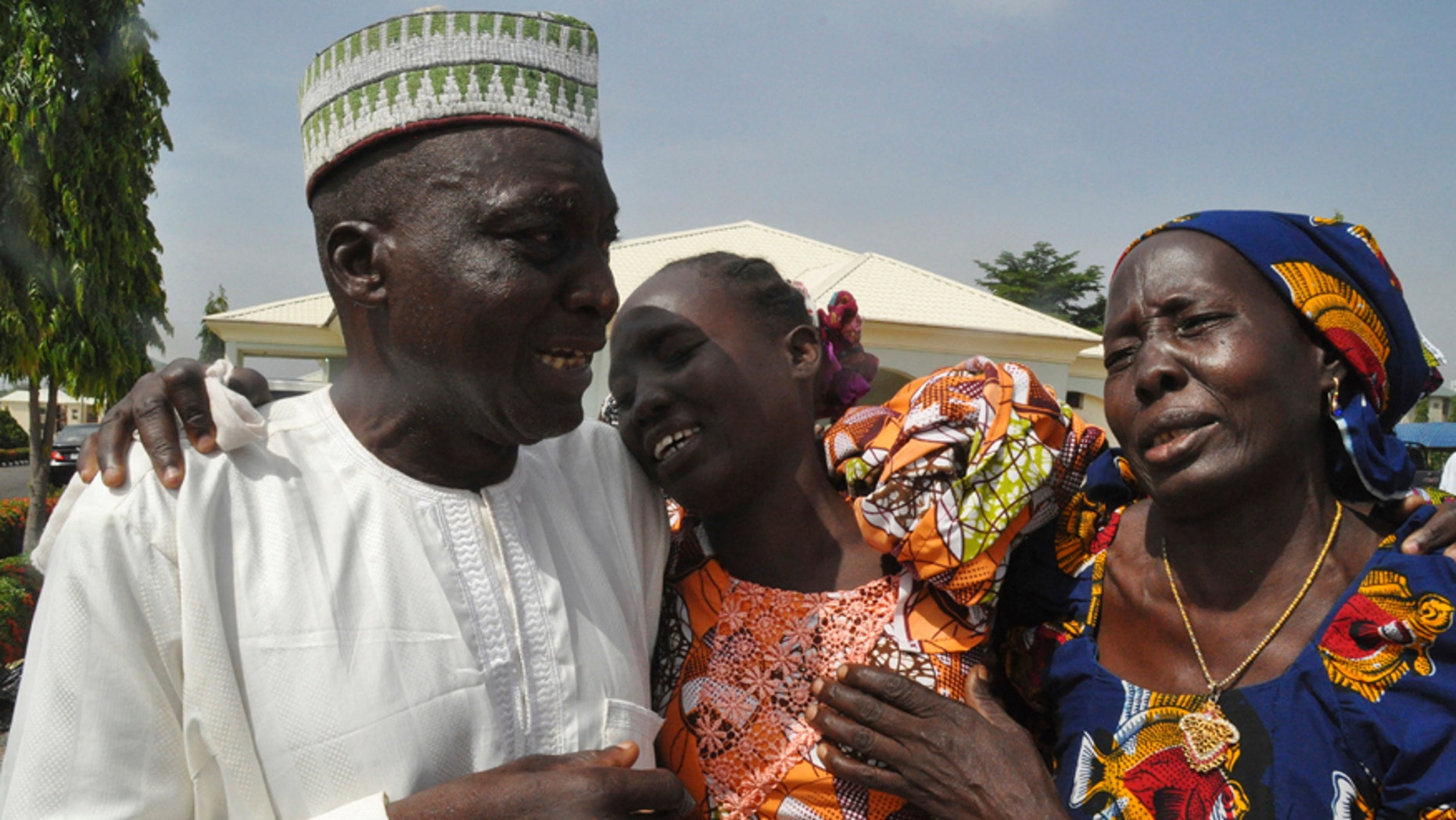 Family members celebrate as they embrace a relative, one of the released kidnapped schoolgirls, in Abuja, Nigeria, Saturday, May 20, 2017. ?The 82 Nigerian schoolgirls recently released after more than three years in Boko Haram captivity reunited with their families for the first time Saturday, as anxious parents looked for signs of how deeply the extremists had changed their daughters' lives. (AP Photo/Olamikan Gbemiga)