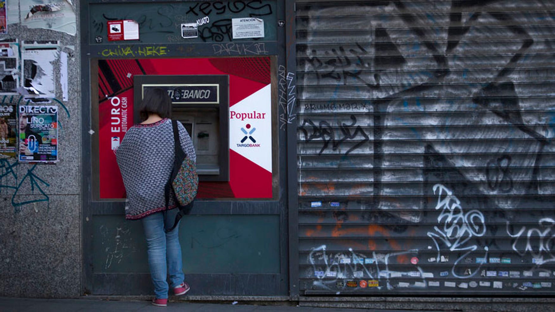 A woman uses a Banco Popular's ATM in Madrid, Wednesday, June 7, 2017. Spain's Banco Santander has acquired Banco Popular, the troubled lender that lost more than half of its shares value over the past week. (AP Photo/Francisco Seco)