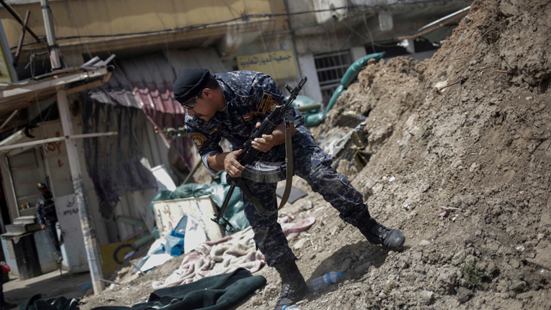 FILE - In this April 29, 2017 file photo, an Iraqi Federal Policeman runs away after he fired shots at an Islamic State group position on the western side of Mosul, Iraq. Iraqi security officials said Wednesday, June 14, 2017 that more than 100 Islamic State militants launched a counterattack in Mosul, killing several Federal Police and civilians in clashes that were still underway. (AP Photo/Bram Janssen, File)