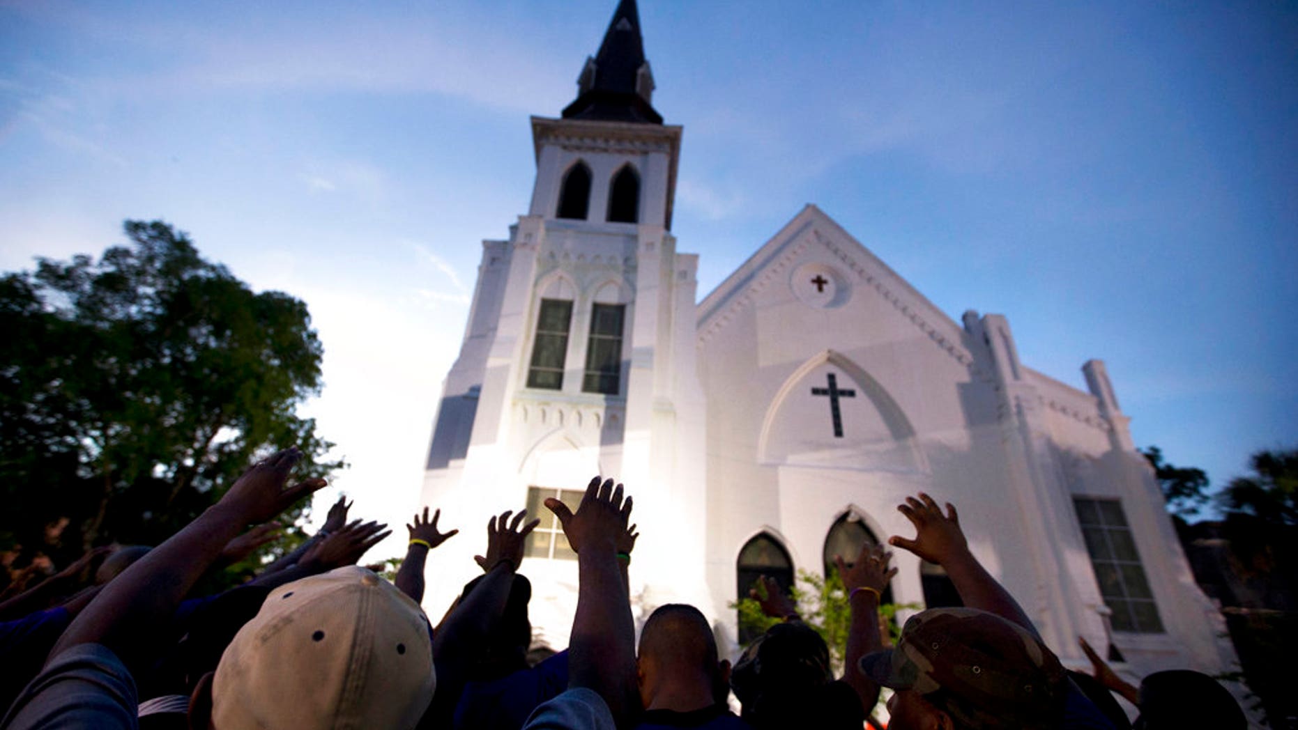 The men of Omega Psi Phi fraternity lead a crowd of people in prayer outside the Emanuel AME Church, after a memorial for the nine people killed by Dylann Roof in Charleston, S.C. June 17, 2017. (AP Photo/Stephen B. Morton)