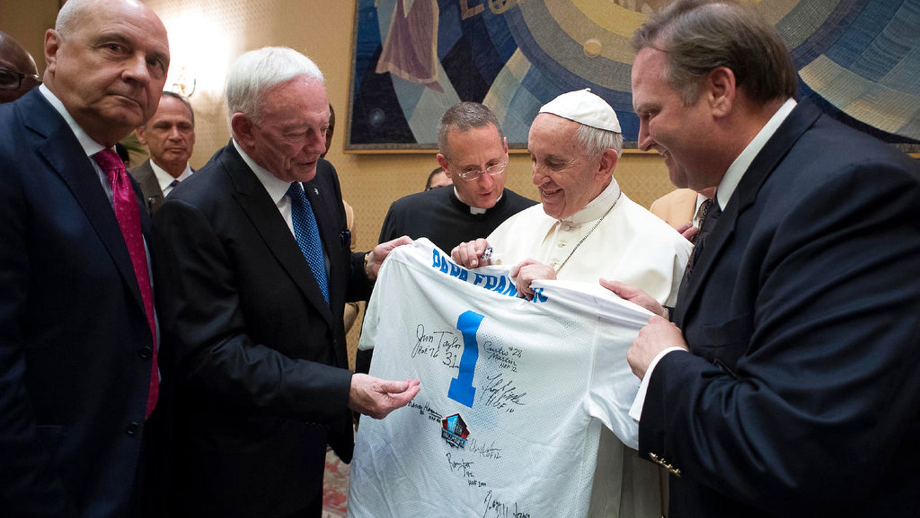 Pope Francis is presented with a Pro Football Hall of Fame jersey bearing his name by Dallas Cowboys owner Jerry Jones, second from left, during a private audience with an NFL Hall of Fame delegation at the Vatican, Wednesday, June 21, 2017. (L'Osservatore Romano/Pool Photo via AP)