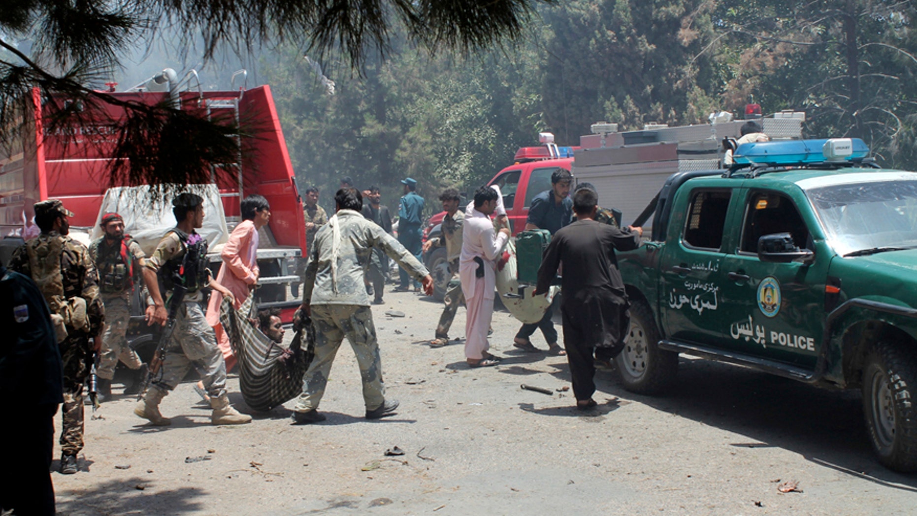Afghans carry an injured man after a suicide car bombing in Helmand province southern of Kabul, Afghanistan, Thursday, June 22, 2017. The bomber struck outside a bank, targeting Afghan troops and government employees waiting to collect their salaries ahead of a major Muslim holiday and killing at least two dozen people, officials said. (AP Photo/Abdul Khaliq)