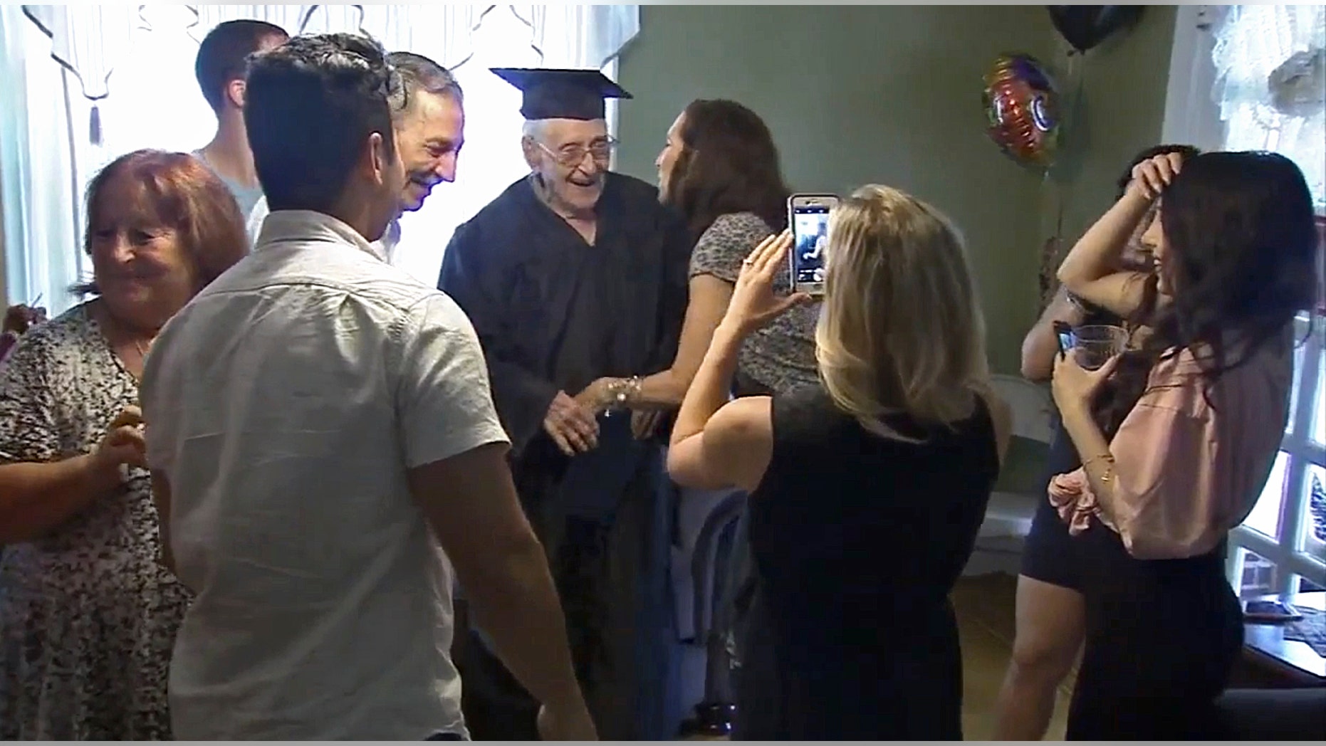 Charles Leuzzi, center, a 97-year-old World War II veteran, is congratulated by friends and relatives after receiving an honorary high school diploma.