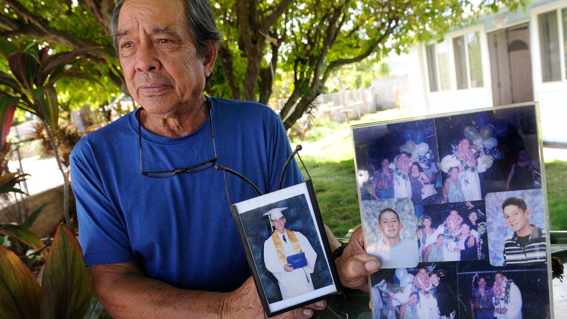 In this July 10, 2017 photo, Clifford Kang, father of soldier Ikaika E. Kang, poses with photos of his son in Kailua, Hawaii. Ikaika E. Kang, an active-duty U.S. soldier, was arrested over the weekend on terrorism charges that accuse him of pledging allegiance to the Islamic State group and saying he wanted to "kill a bunch of people." Ikaika E. Kang is scheduled to appear in federal court for an arraignment Monday, July 24, 2017. (Bruce Asato/The Star-Advertiser via AP)