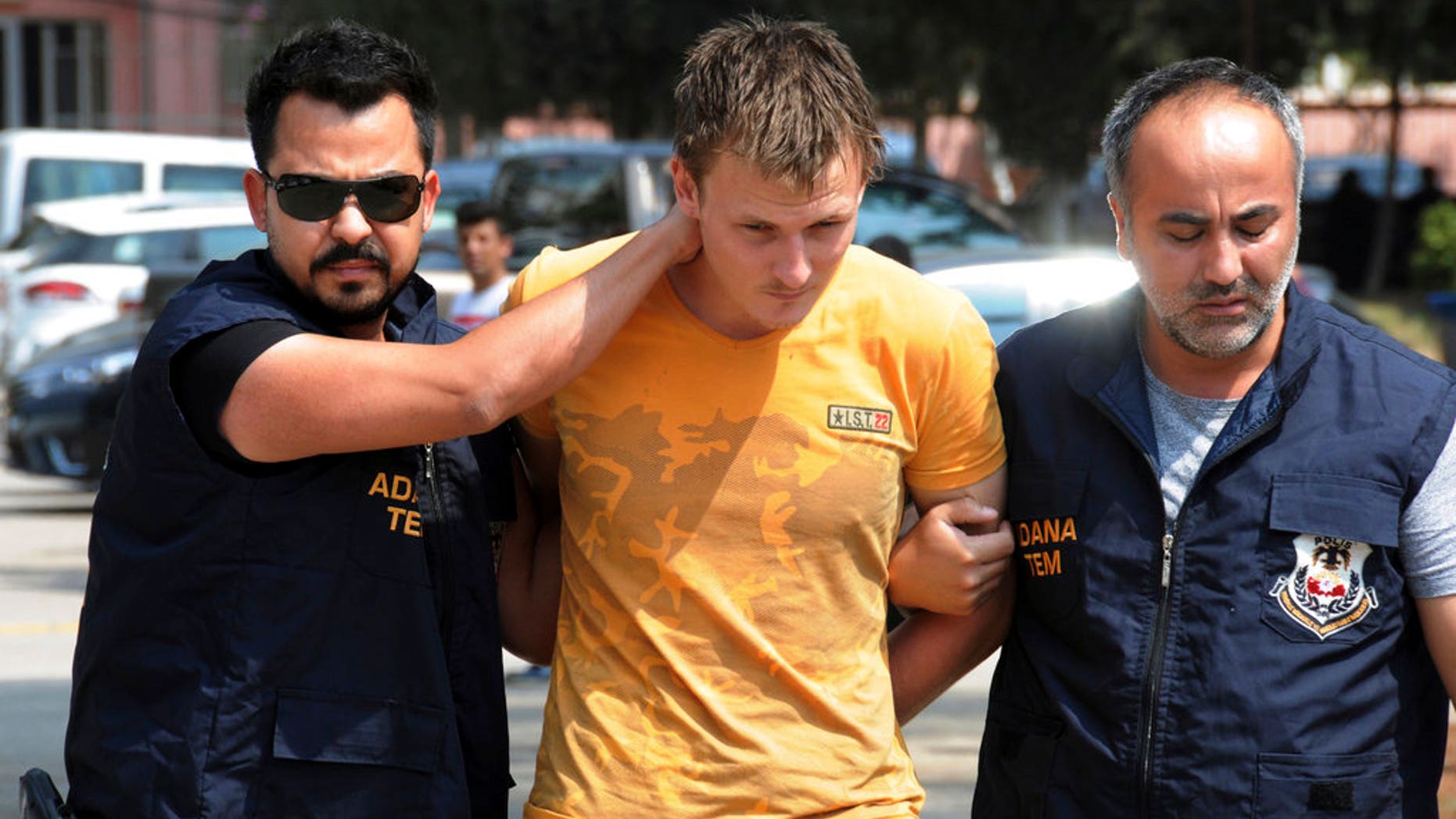 Turkish police walk with a handcuffed Renad Bakiev, center.