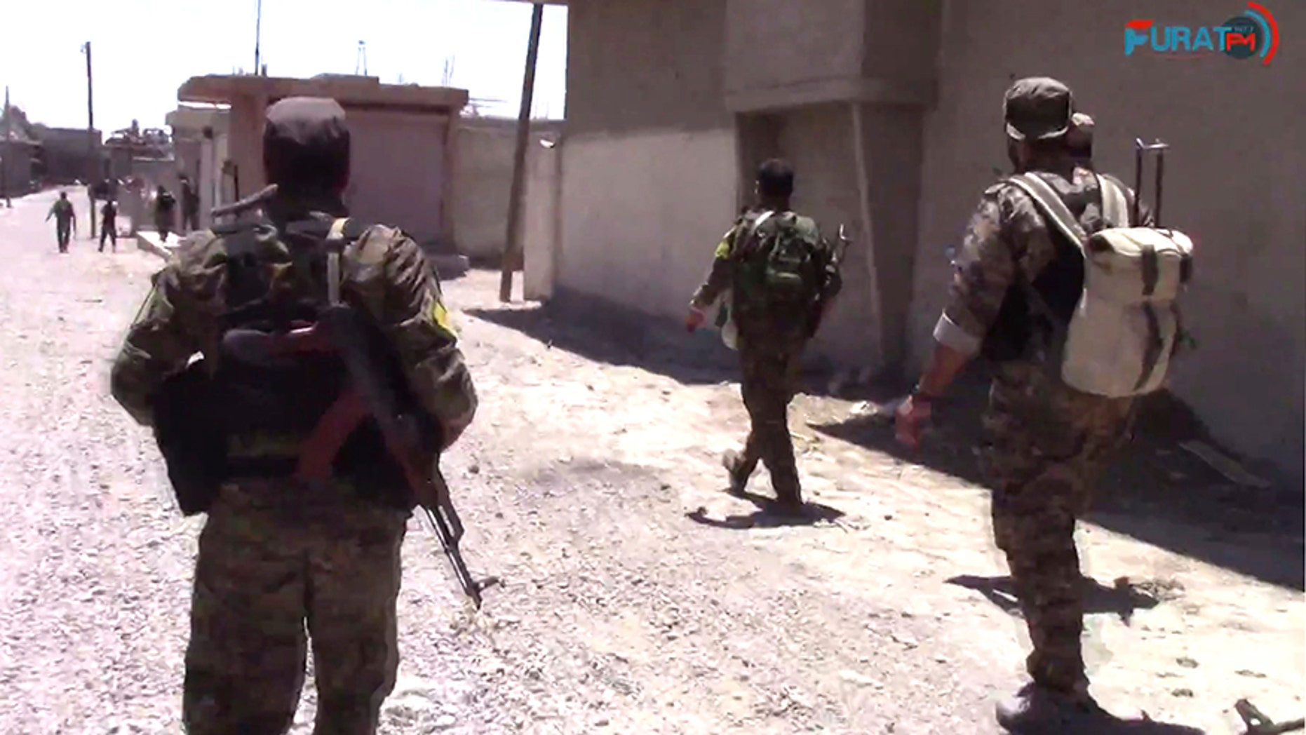 This frame grab from video released Friday, Aug. 11, 2017, and provided by Furat FM, a Syrian Kurdish activist-run media group, shows U.S.-backed Syrian Democratic Forces (SDF) fighters advance in Raqqa, Syria. U.S.-backed Syrian fighters advancing from eastern and western parts of the northern city of Raqqa have linked up for the first time in weeks after launching their offensive against Islamic State group fighters there. (Furat FM, via AP)