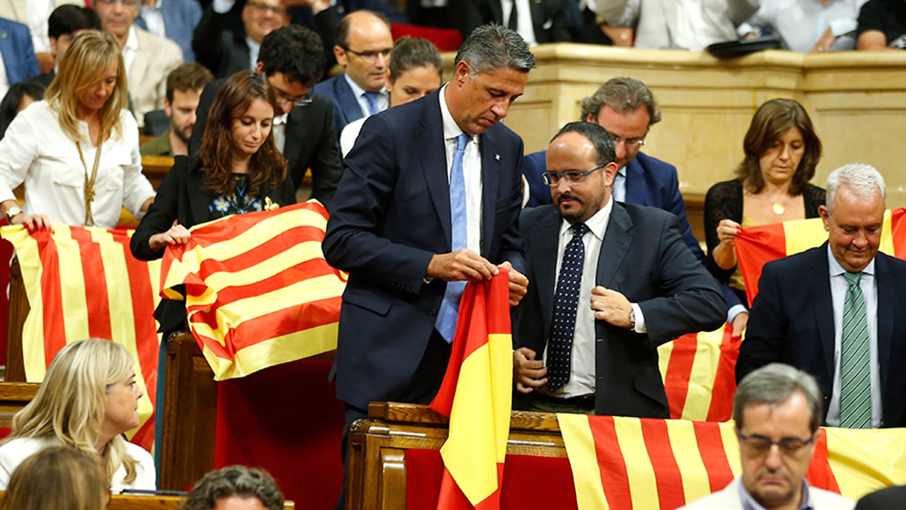Members of the Catalan Popular Party display Spanish flags just before abandoning the session ahead of the voting, during a plenary session at the Parliament of Catalonia in Barcelona, Spain, Wednesday, Sept. 6, 2017. Catalan lawmakers are voting on a bill that will allow regional authorities to officially call an Oct. 1 referendum on a split from Spain, making concrete a years-long defiance of central authorities, who see the vote as illegal. (AP Photo/Manu Fernandez)