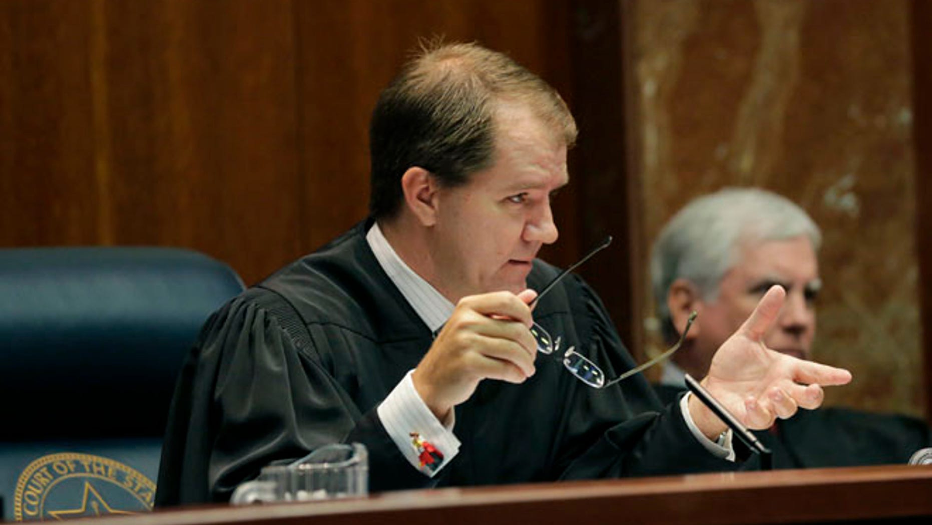 Texas Supreme Court Justice Don Willett, left, asks a question during oral arguments at the state Supreme Court in Austin, Texas.