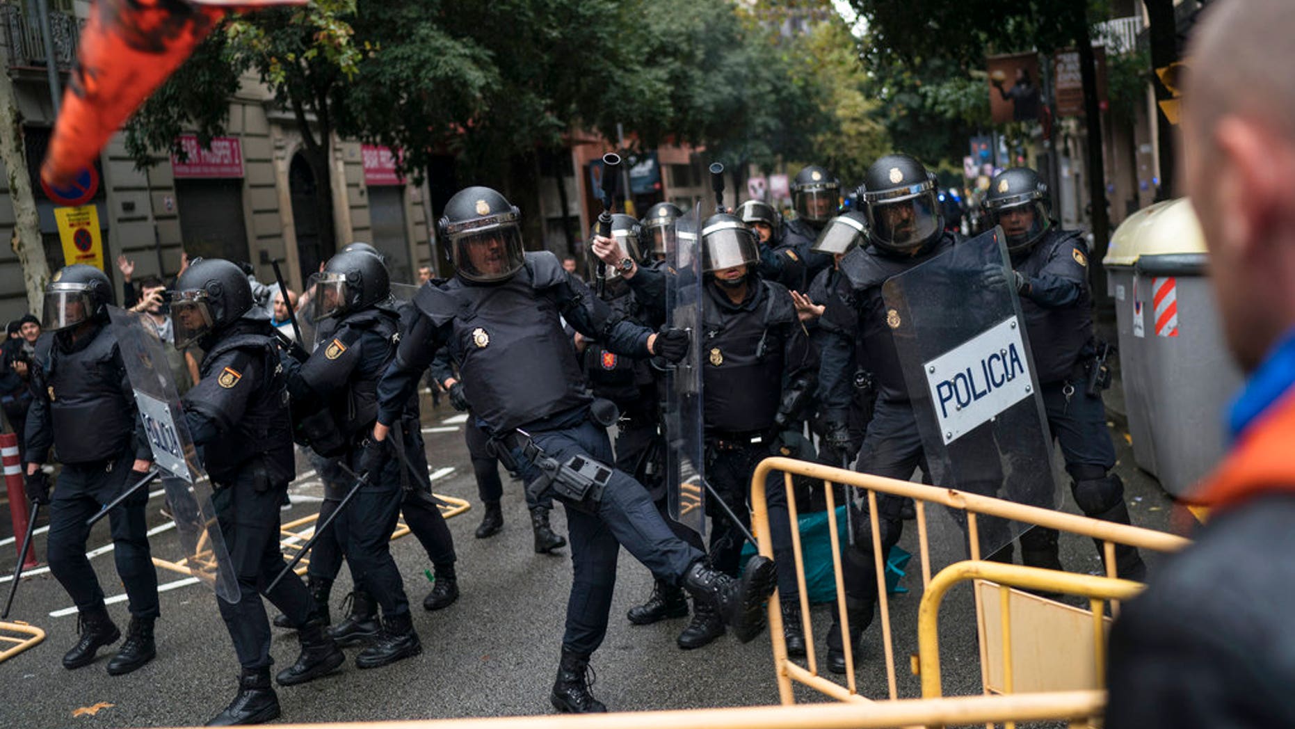 Spanish riot police removes fences thrown by people to them as they try to prevent people from reaching a voting site at a school assigned to be a polling station by the Catalan government in Barcelona, Spain, Sunday, 1 Oct. 2017. Catalan pro-referendum supporters vowed Saturday to ignore a police ultimatum to leave the schools they are occupying to use in a vote seeking independence from Spain. (AP Photo/Felipe Dana)