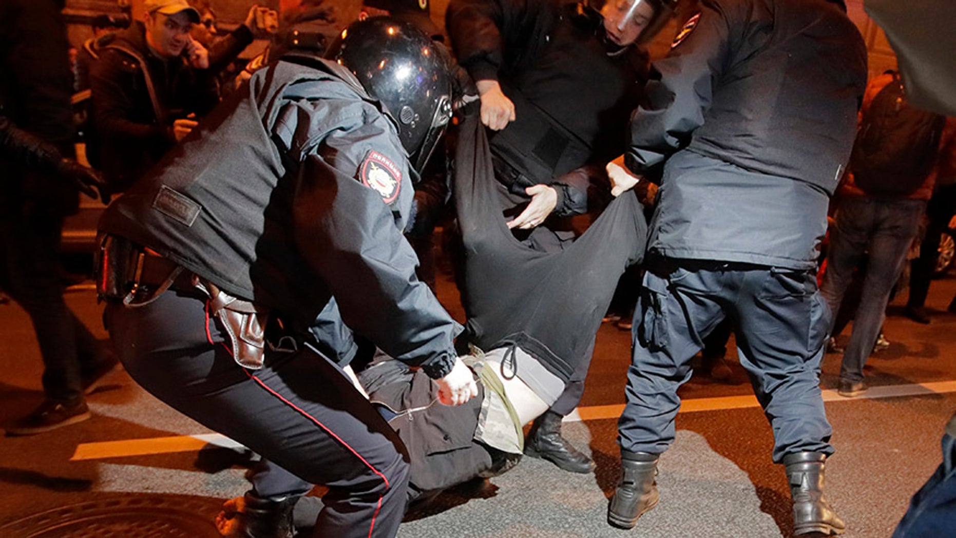 Riot police officers detain a protester during a rally in St.Petersburg, Russia, Saturday, Oct. 7, 2017. Supporters of opposition leader Alexei Navalny rallied across Russia on Saturday, heeding his call to pressure authorities into letting him enter the presidential race with a wave of demonstrations on President Vladimir Putin's 65th birthday. (AP Photo/Dmitri Lovetsky)