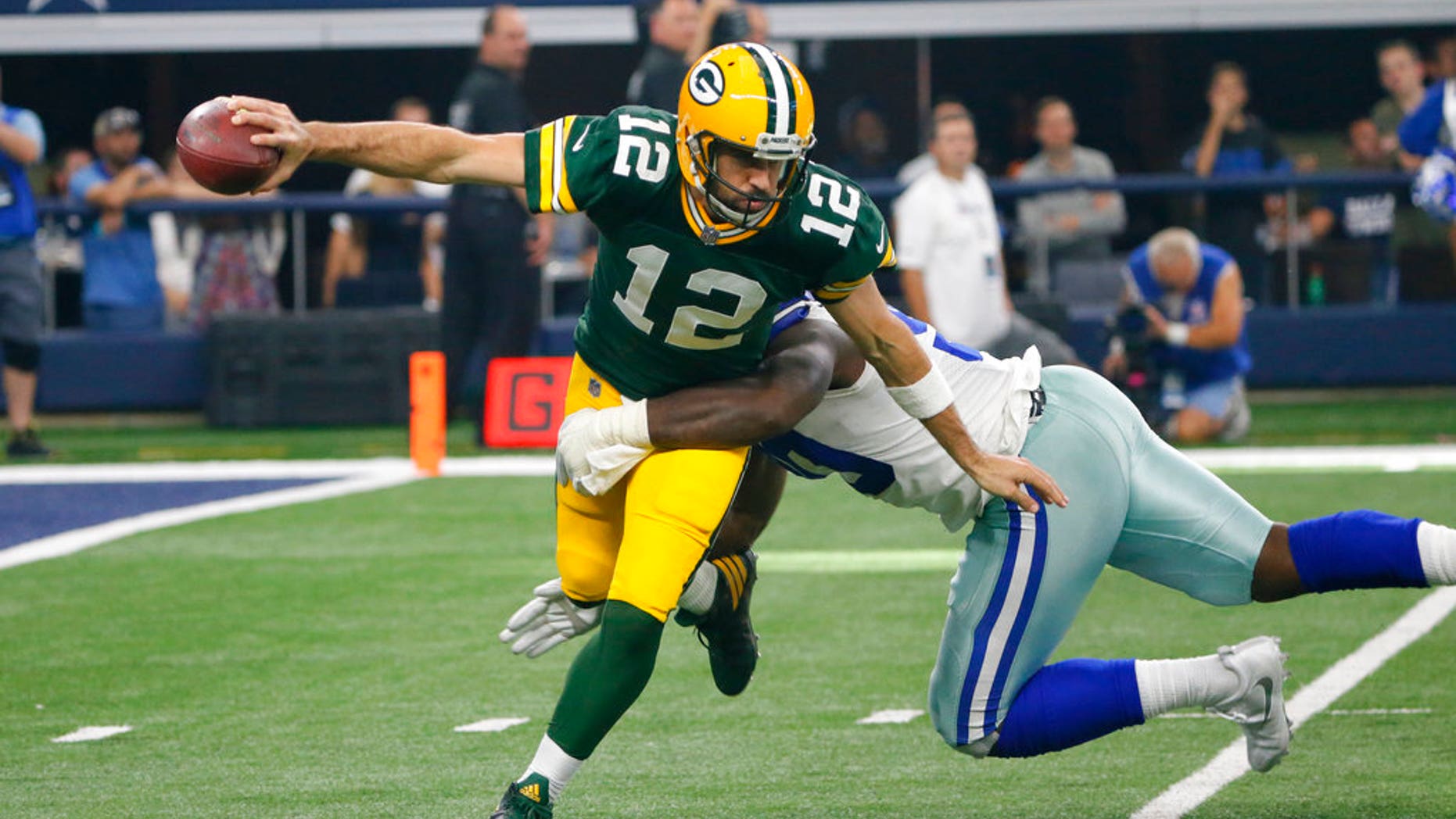 Green Bay Packers quarterback Aaron Rodgers (12) attempts to escape the grasp of Dallas Cowboys defensive end DeMarcus Lawrence (90) before throwing a pass during an NFL football game, Sunday, Oct. 8, 2017, in Arlington, Texas. (AP Photo/Roger Steinman)