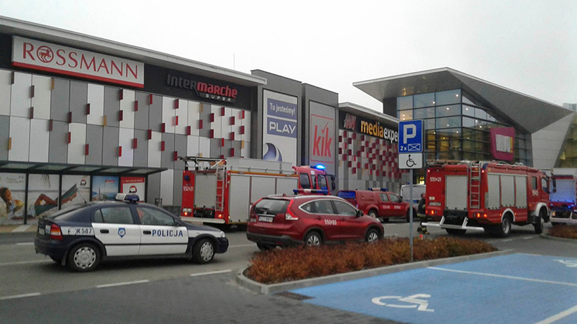 Police and firefighters' cars and trucks stand in front of the VIVO! shopping mall where a 27-year-old man attacked people with a knife killing one person and injuring several others in Stalowa Wola, southeastern Poland, on Friday, Oct. 20, 2017. (AP Photo/Rafal Baran)