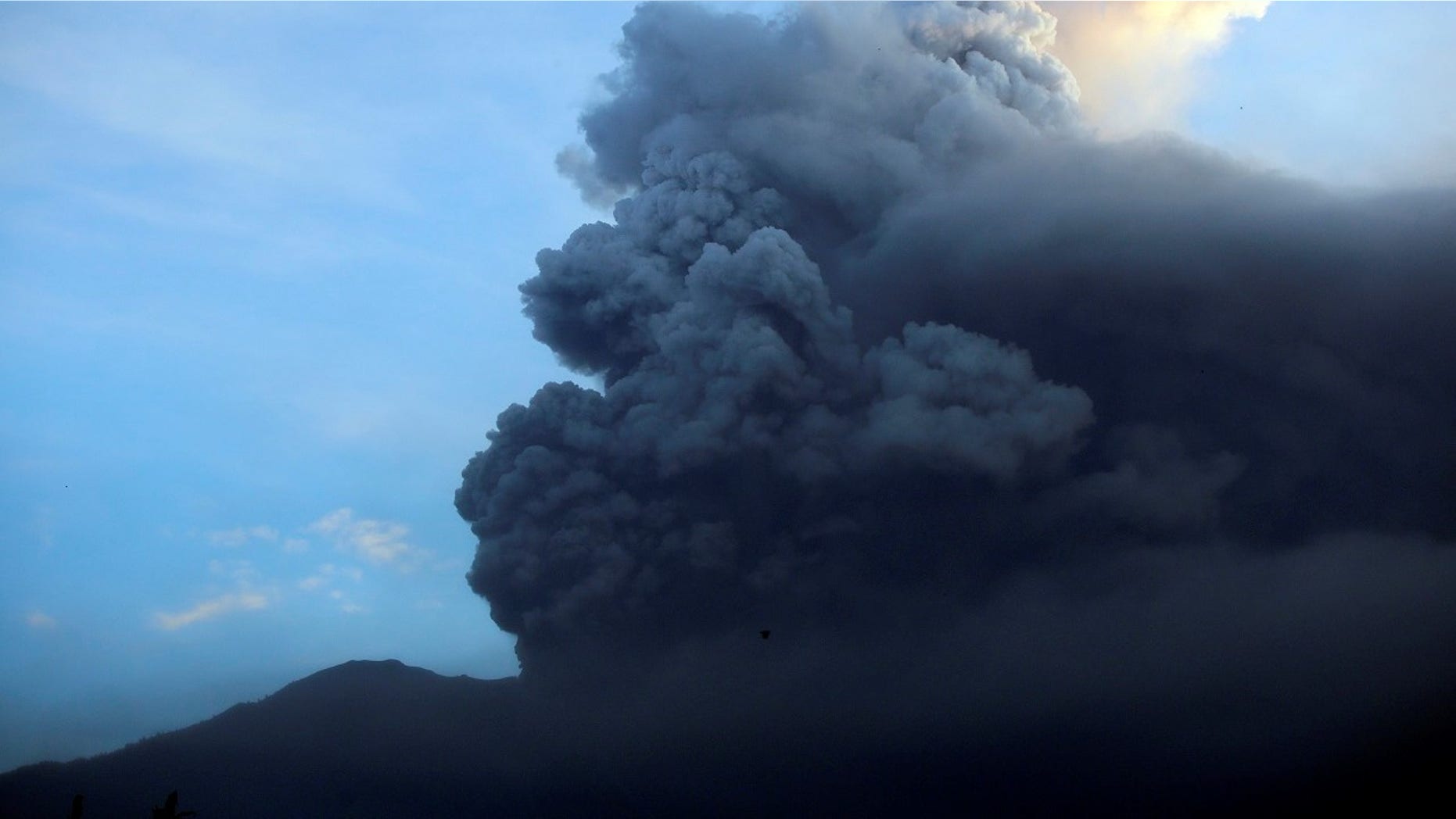 A view of the Mount Agung volcano erupting at sunrise in Karangasem, Bali island, Indonesia, Sunday, Nov. 26, 2017. A volcano on the Indonesian tourist island of Bali erupted for the second time in a week on Saturday, disrupting international flights even as authorities said the island remains safe. (AP Photo/Firdia Lisnawati)