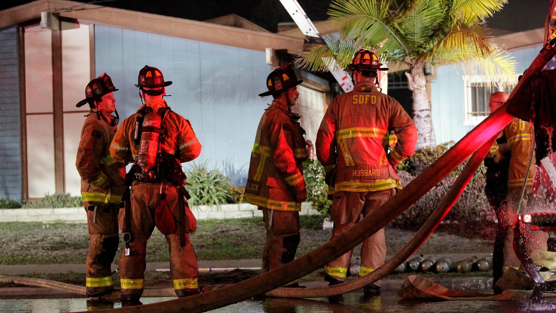 Firefighters gather outside a San Diego house where a small plane crashed, Dec. 9, 2017.