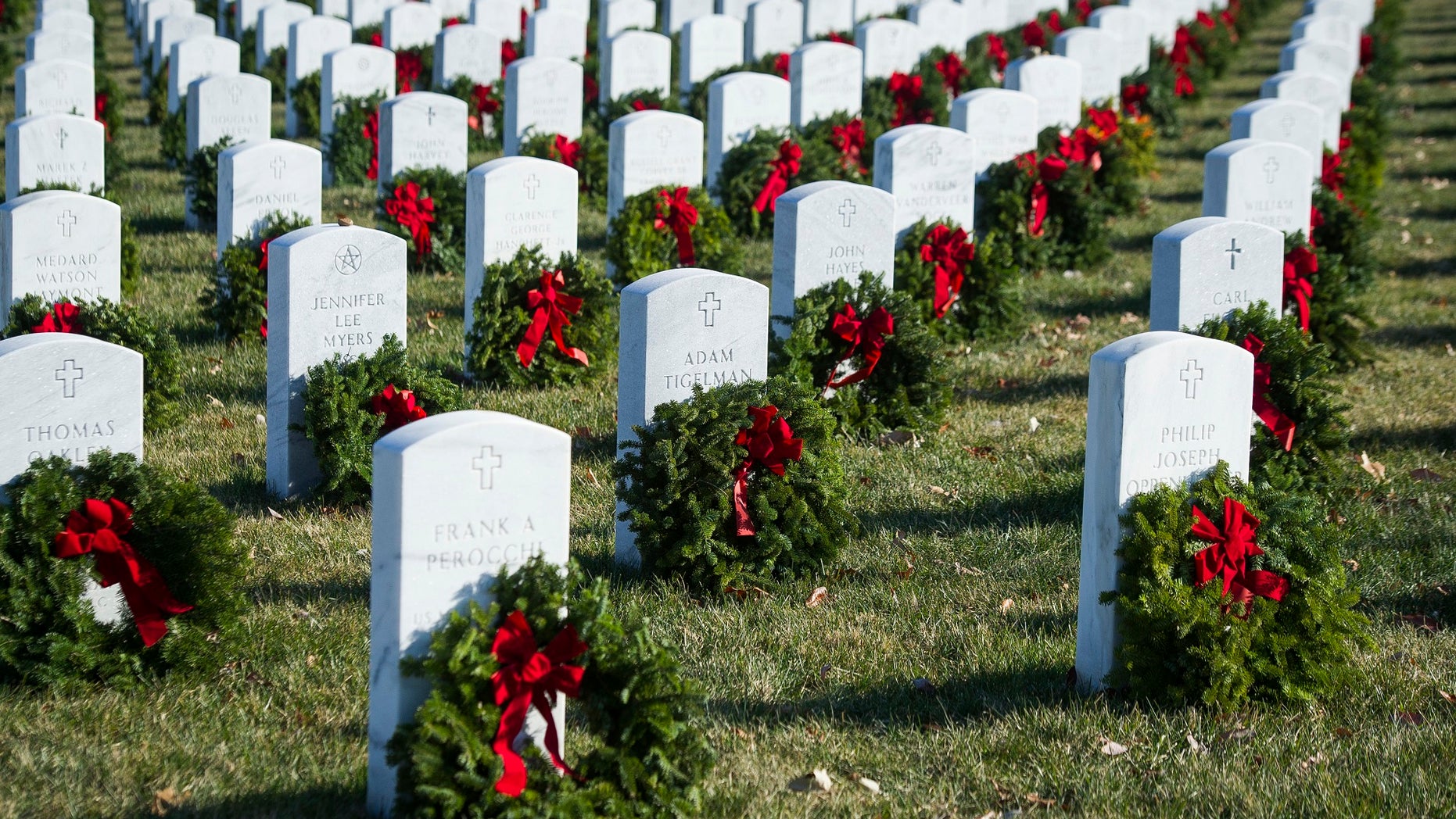 Wreaths rest against headstones at Arlington National Cemetery as Wreaths Across America places remembrance wreaths on headstones at the cemetery in Arlington, Va., Saturday, Dec. 16, 2017.