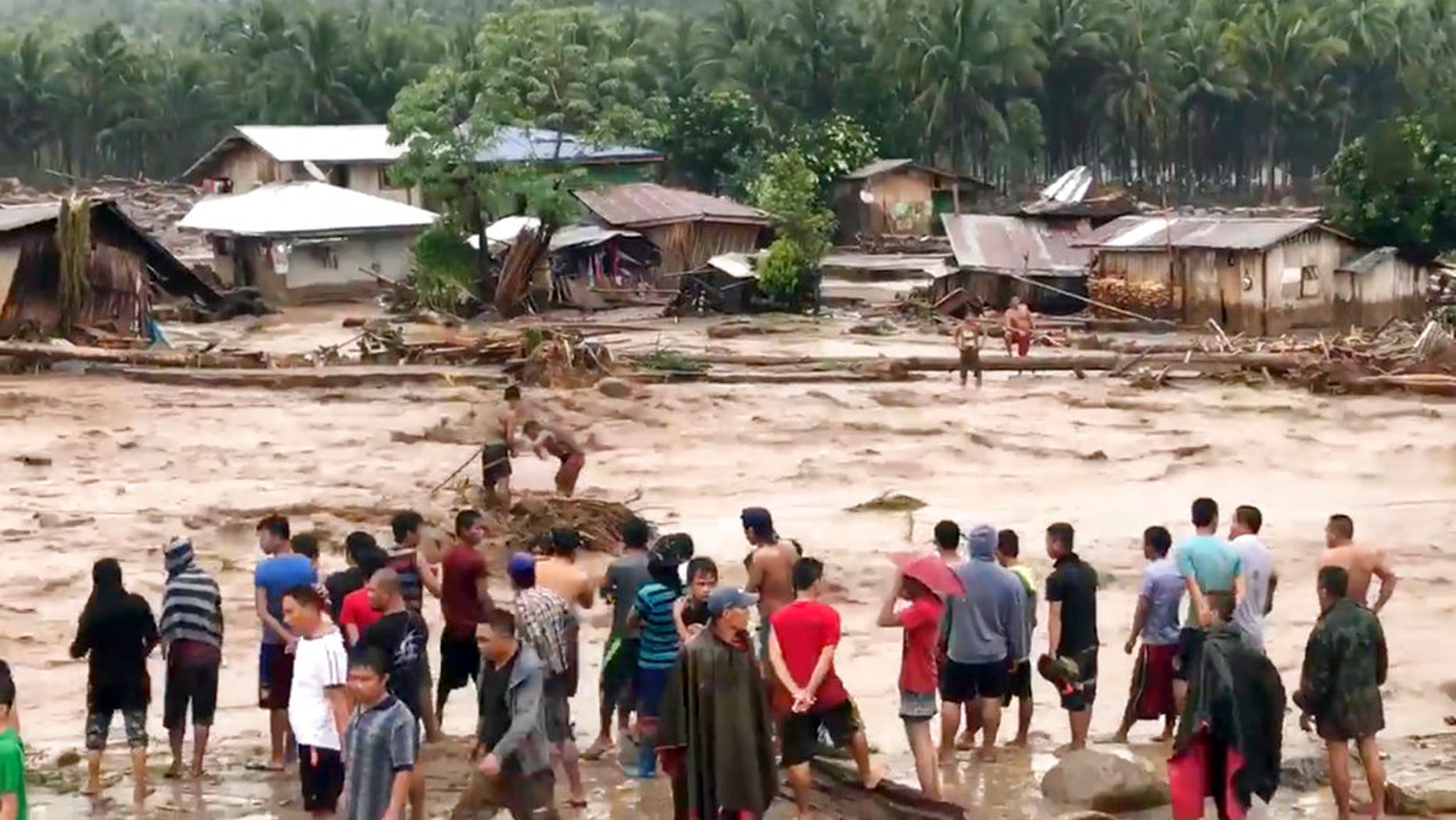 In this photo made from video by Aclimah Disumala, Friday, Dec. 22, 2017, villagers carry cross raging flood waters in Lanao del Norte, Zamboanga Pennisula, southern Philippines. A tropical storm has unleashed flash floods and set off landslides in the southern Philippines leaving dozens of people dead. (Aclimah Disumala via the AP)