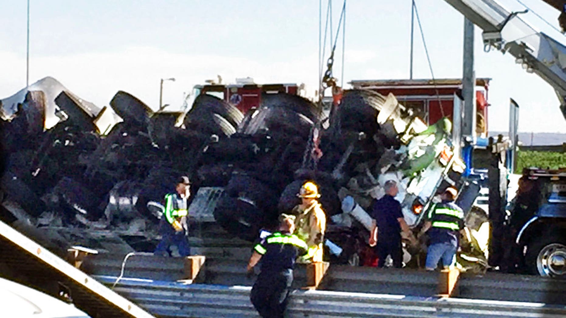 A crane lifts a truck off a passenger car after a semi-truck crashed through a guardrail and slammed into oncoming traffic in Rialto, Calif., Feb. 16, 2018.
