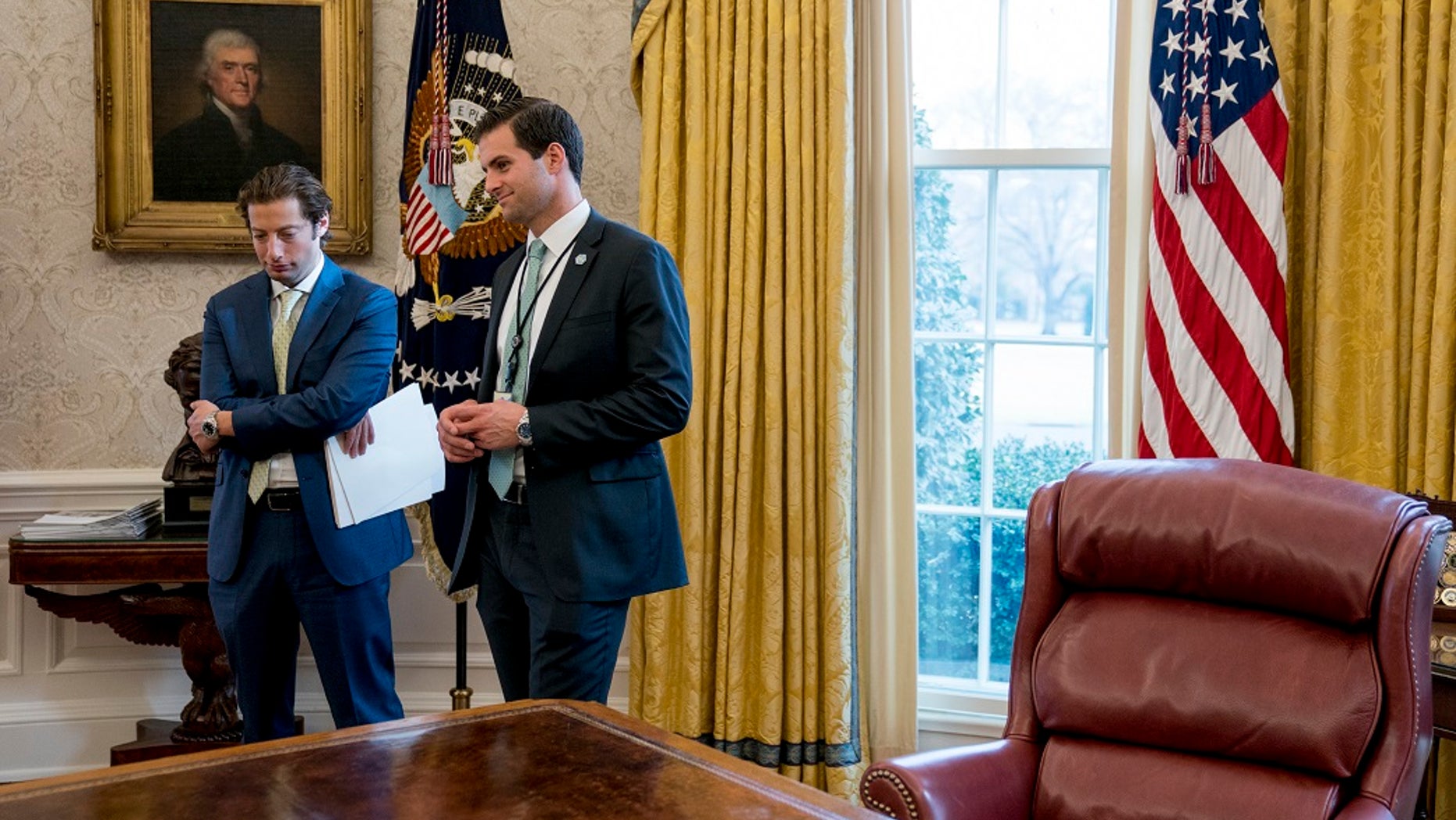 White House aide John McEntee, right, and Treasury Secretary Steve Mnuchin's Chief of Staff Eli Miller, left, stand in the Oval Office as President Donald Trump speaks at a tax reform meeting with American workers at the White House in Washington. Trump's personal aide is leaving the White House and will rejoin his campaign.
