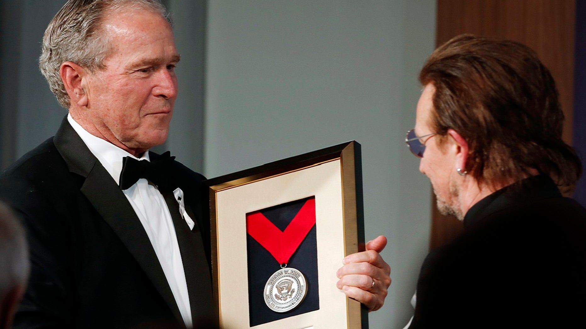 Former President George W. Bush, left, presents a medal of Distinguished Leadership to U2 musician Bono during a gala for the Forum on Leadership at the George W. Bush Institute, Thursday, April 19, 2018, in Dallas.