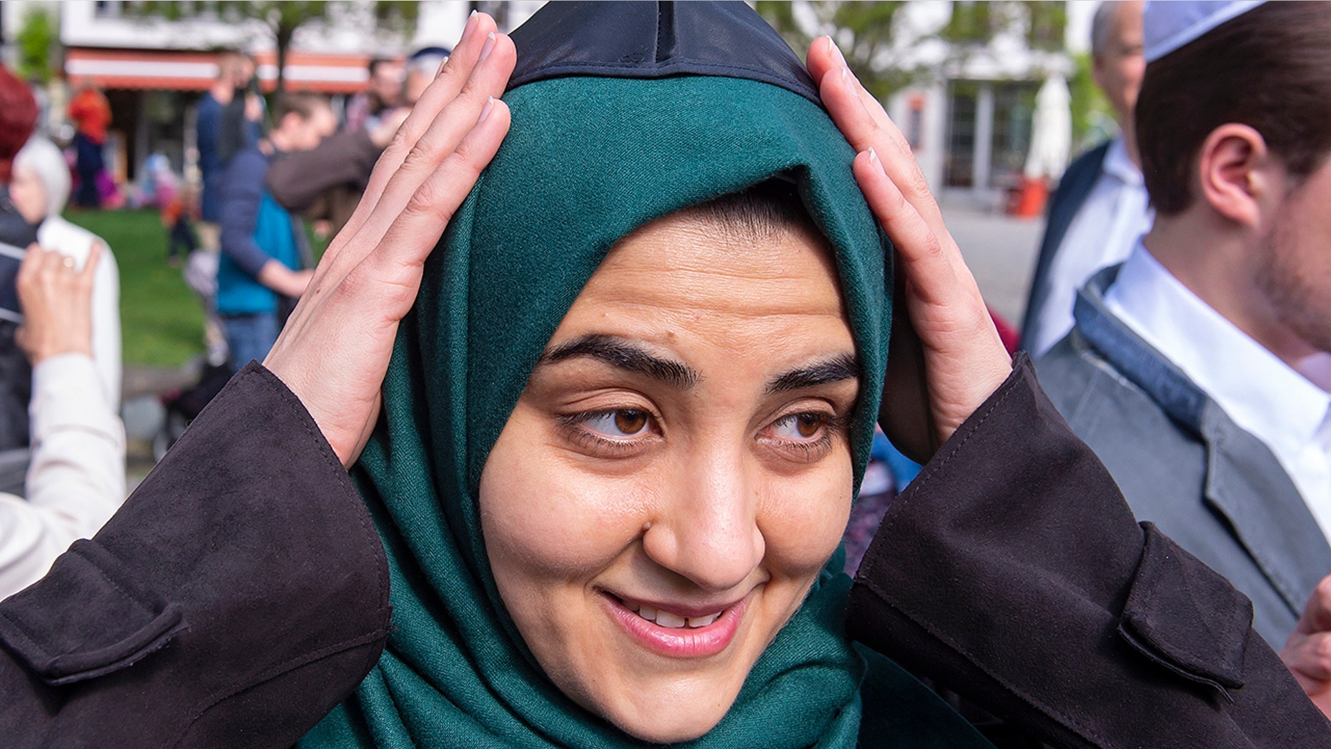 Muslim woman Iman Jamous fixes the Jewish kippah on her head during a demonstration against antisemitism in Germany in Erfurt, Germany, Wednesday, April 25, 2018. (AP Photo/Jens Meyer)