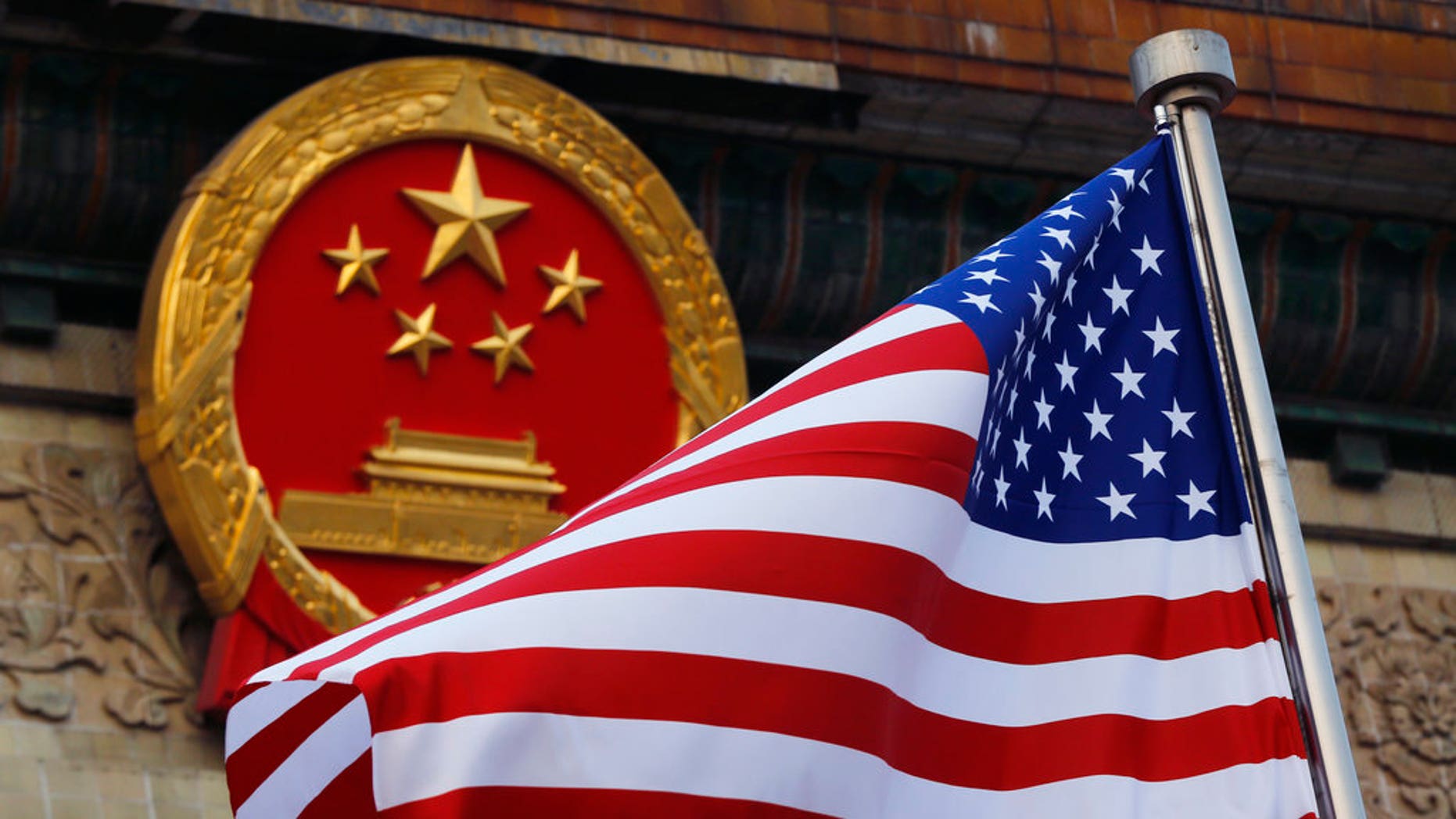 An American flag is flown next to the Chinese national emblem during a welcoming ceremony for visiting U.S. President Donald Trump outside the Great Hall of the People in Beijing.