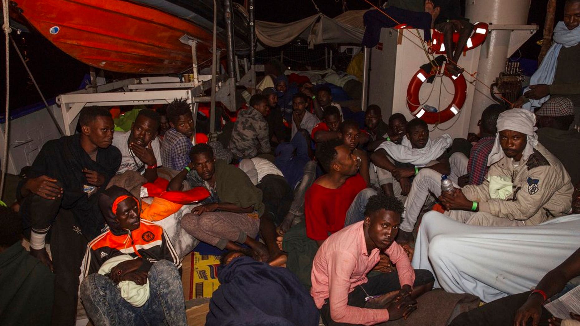 Rescued migrants sit in the search-and-rescue ship of German aid group Mission Lifeline as the boat remained stranded off Malta with 234 migrants aboard and no port at which to dock after both Italy and Malta refused to give authorization, early Monday, June 25; a deal has now been worked out