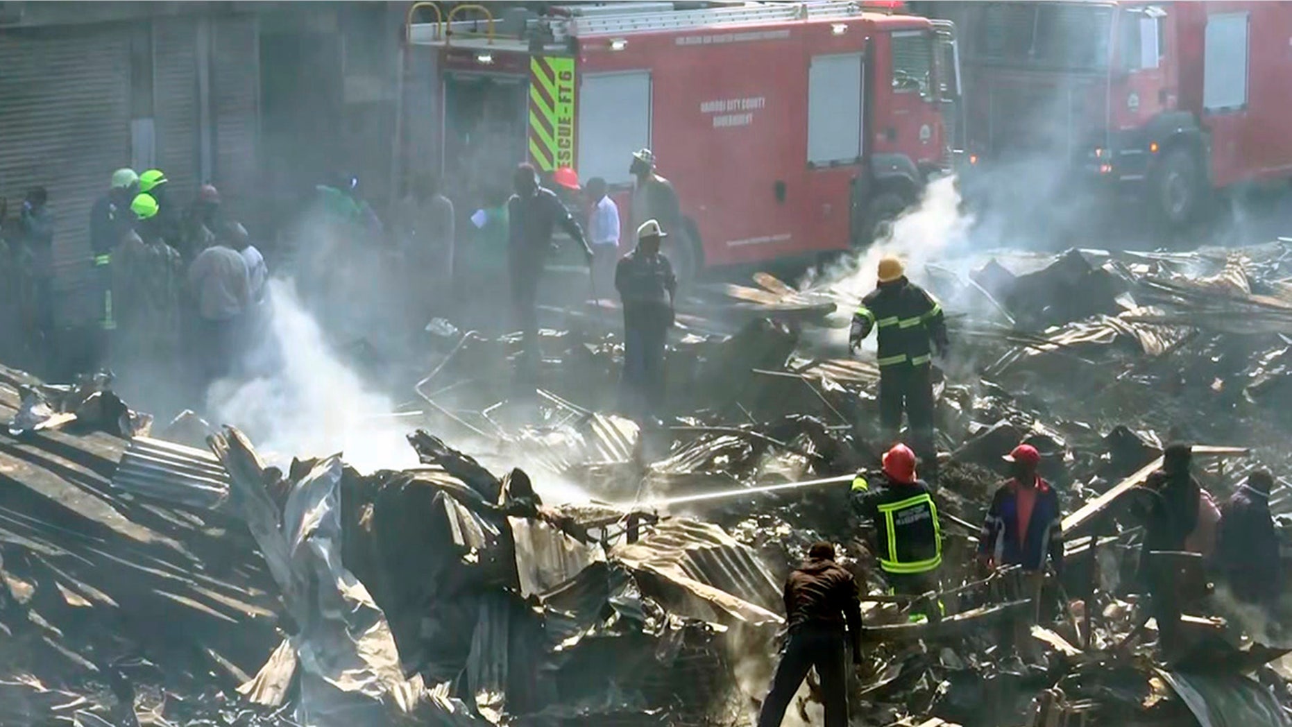 In this image from TV, a fire fighter damps down the charred debris after a fire swept through a marketplace in Nairobi, Kenya, Thursday June 28, 2018. Authorities report that several people are known to have died and about 70 are receiving hospital treatment, with rescue teams still searching for more bodies and survivors in the burned marketplace. (AP Photo)