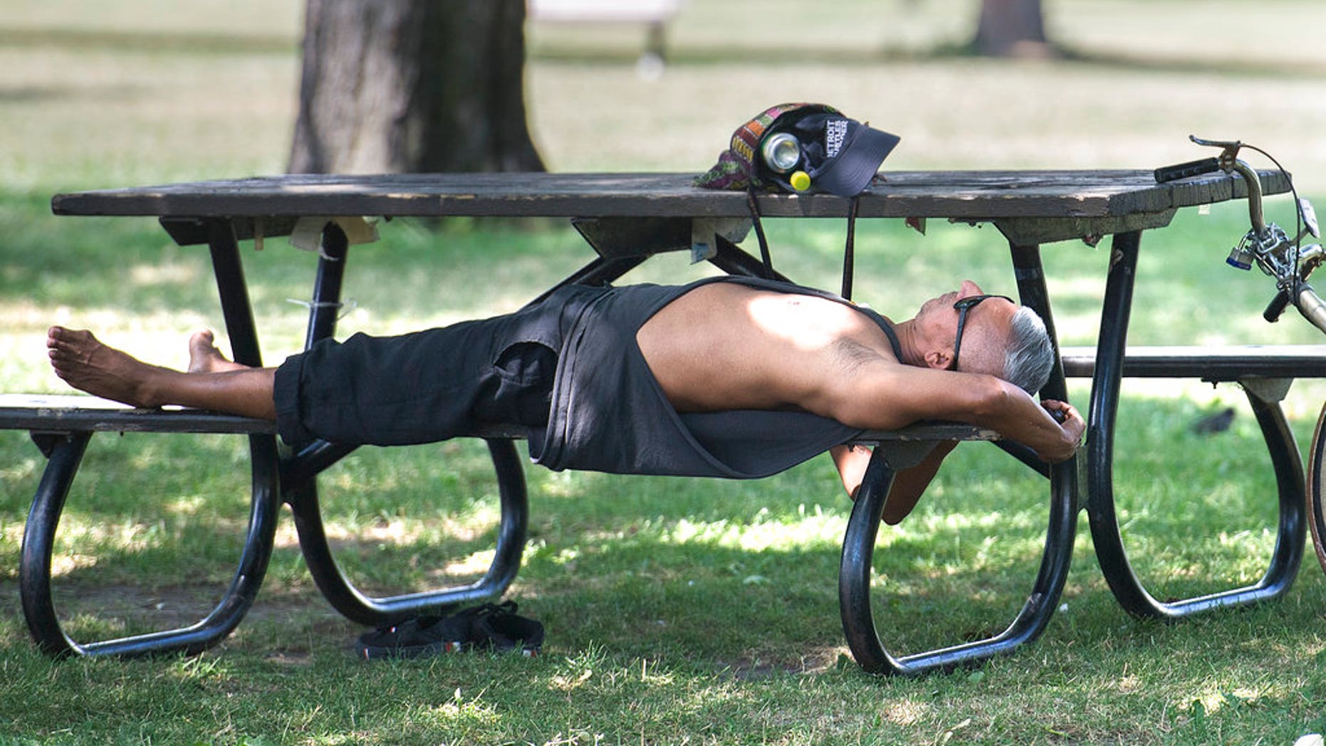 In this Thursday, July 5, 2018 photo, a man relaxes under a tree in a park in Montreal. Heat warnings are in effect across southern Quebec, Ontario and the Atlantic region of the country, but temperatures are expected to drop overnight.