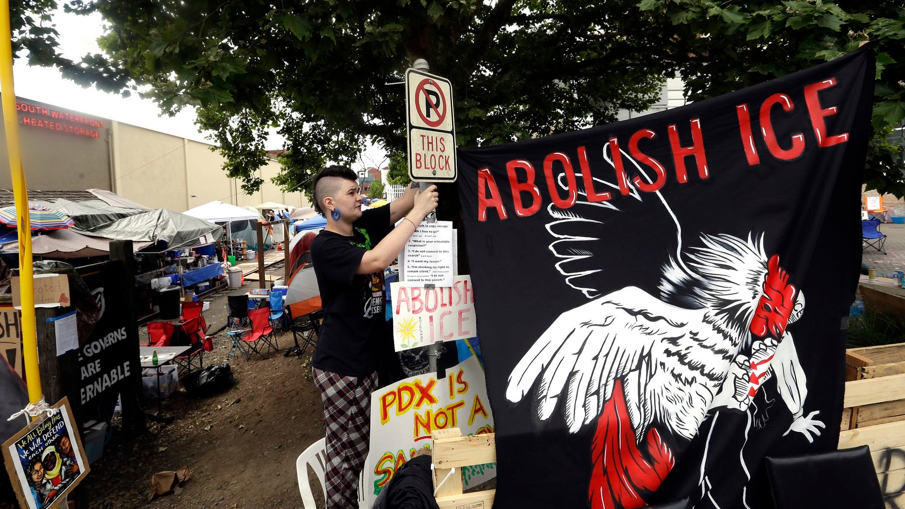 A woman hangs a sign at a protest camp on property outside the U.S. Immigration and Customs Enforcement office in Portland, Oregon.