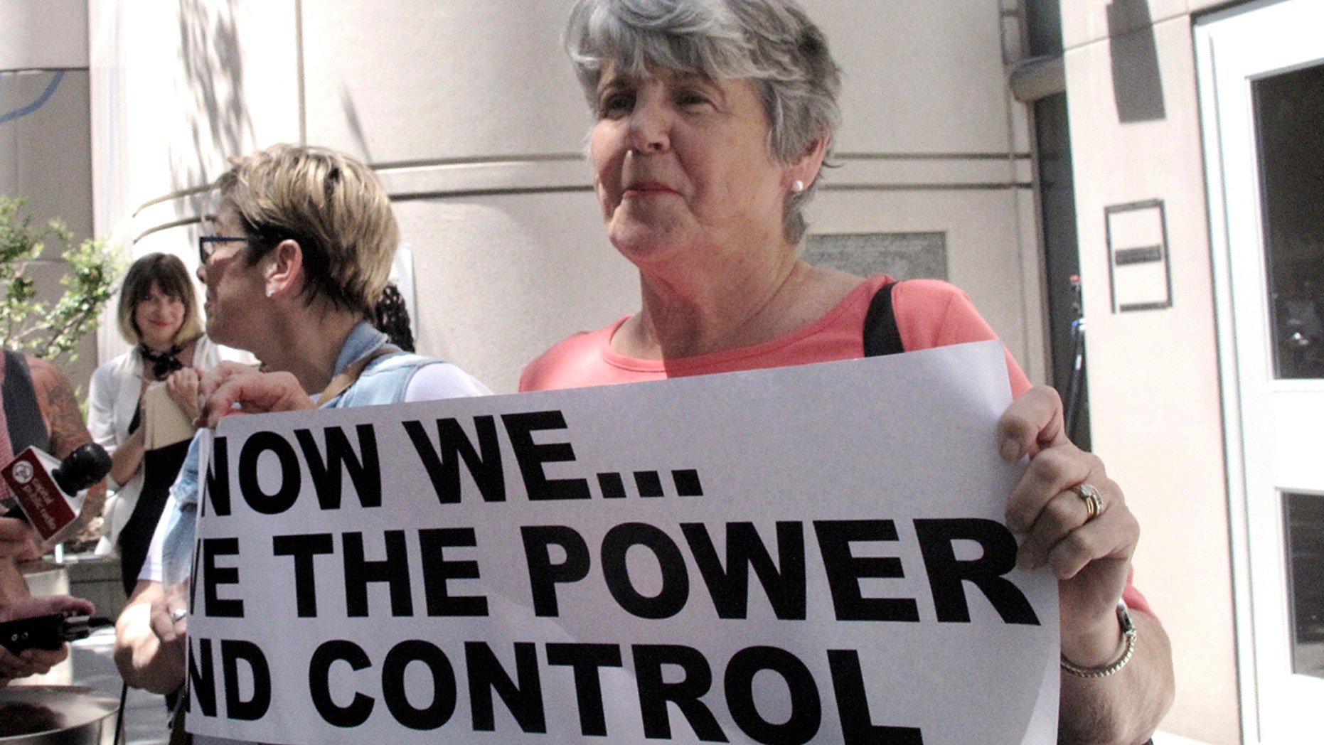 Jane Carson-Sandler, of South Carolina, who was raped in 1976, holds a sign with a message to her alleged attacker, the so-called "Golden State Killer" suspect, in Sacramento, Calif., July 12, 2018.
